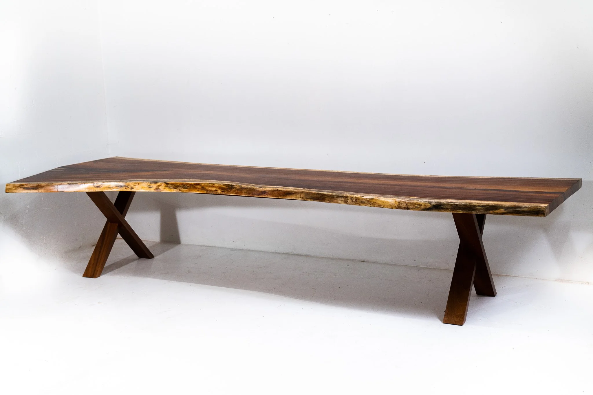 A wooden bench with a natural, unfinished edge design against a plain white background.