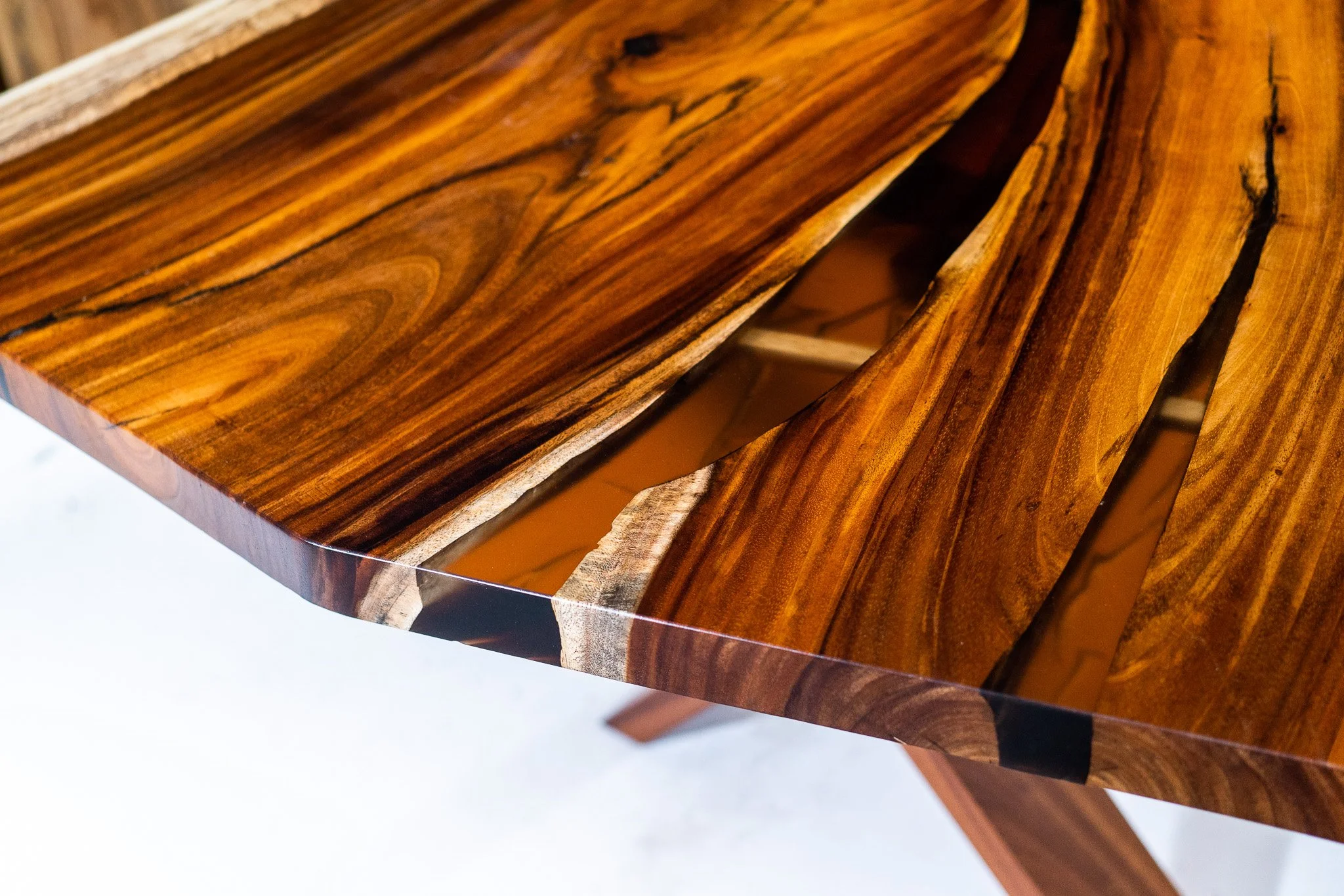 Close-up of a wooden table with a glossy finish and a natural, swirling wood grain pattern.