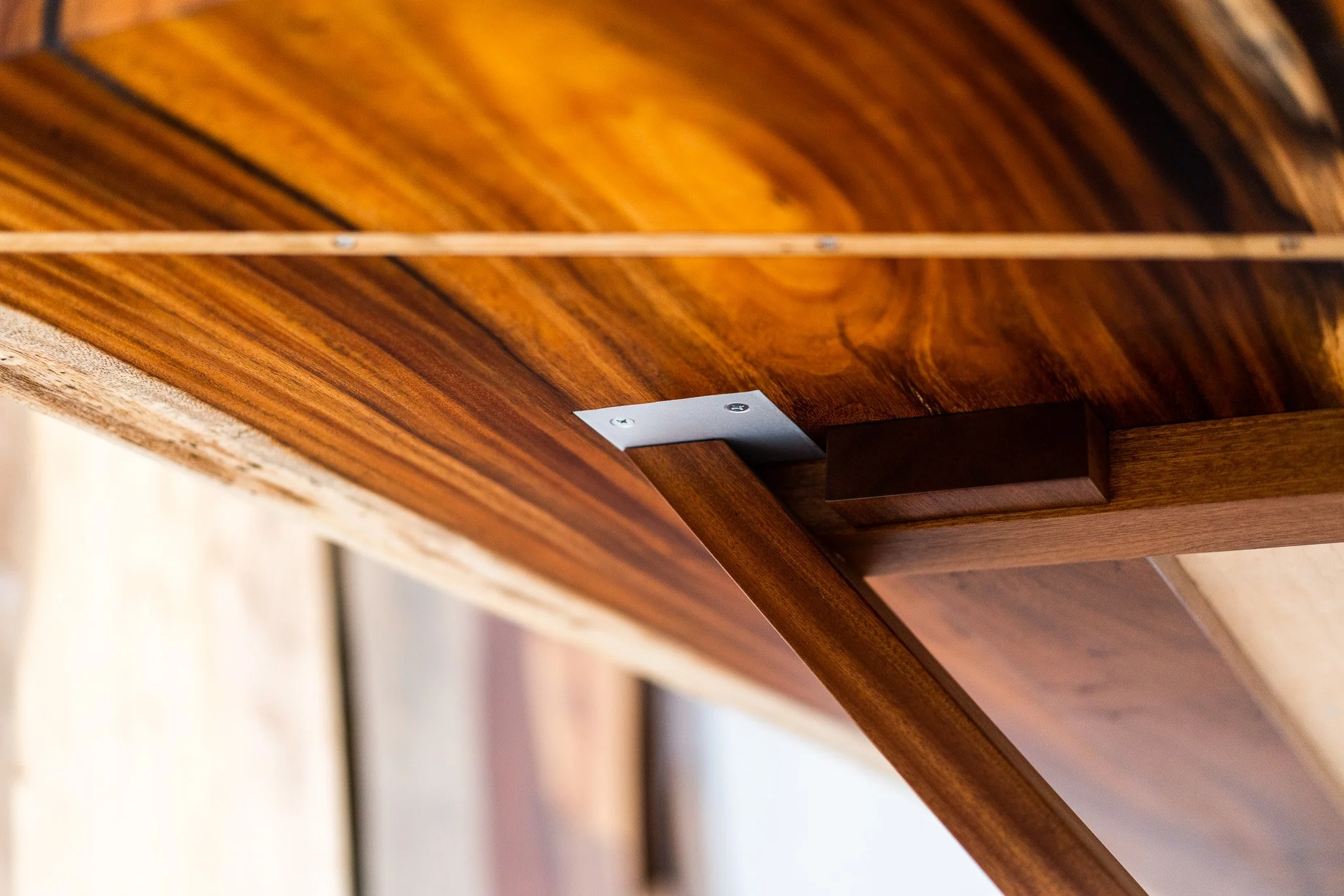Close-up of a wooden table corner showing a metal bracket and wood grain.