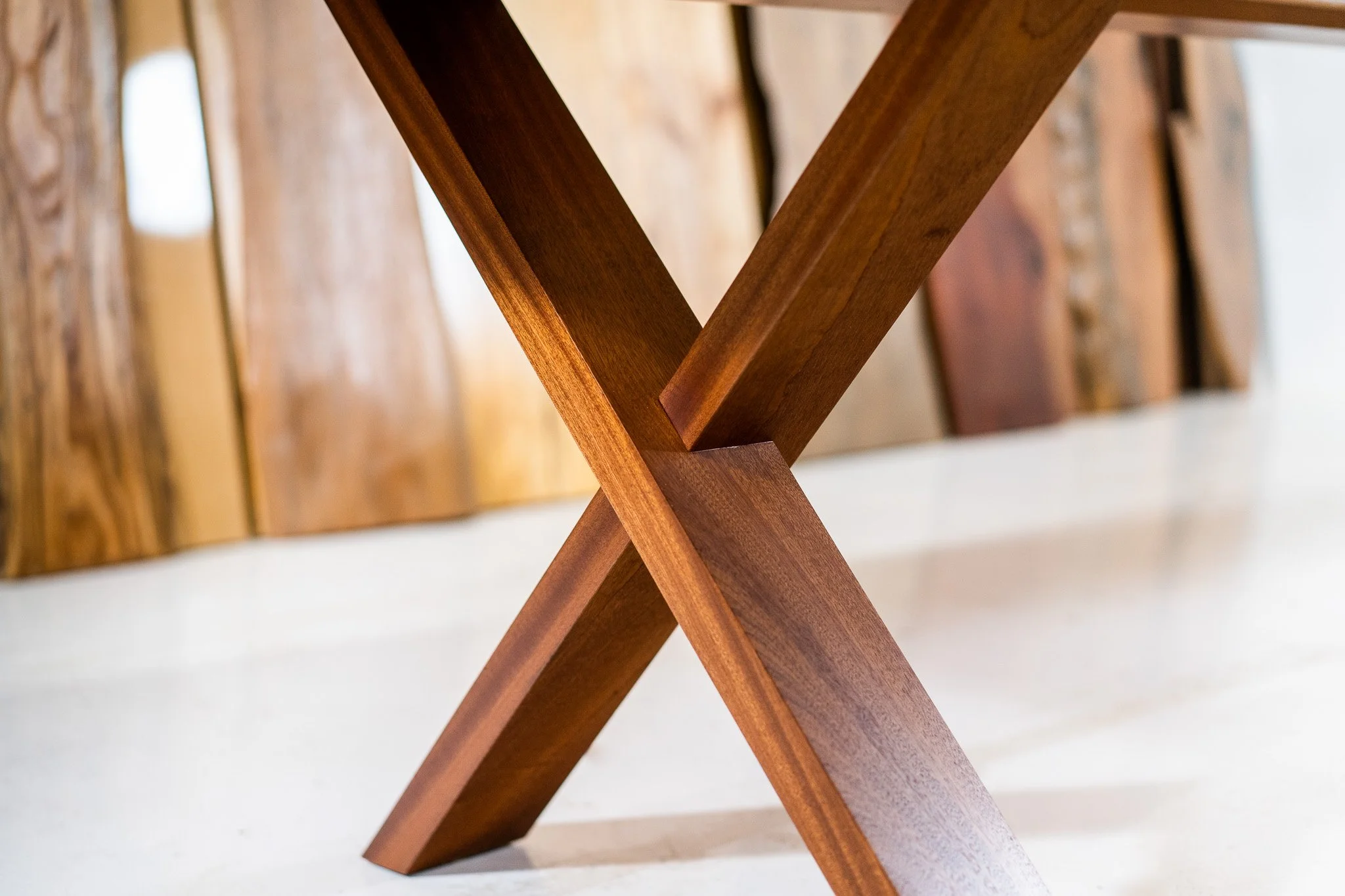 Close-up of a wooden table's leg intersection with a modern, minimalist design.