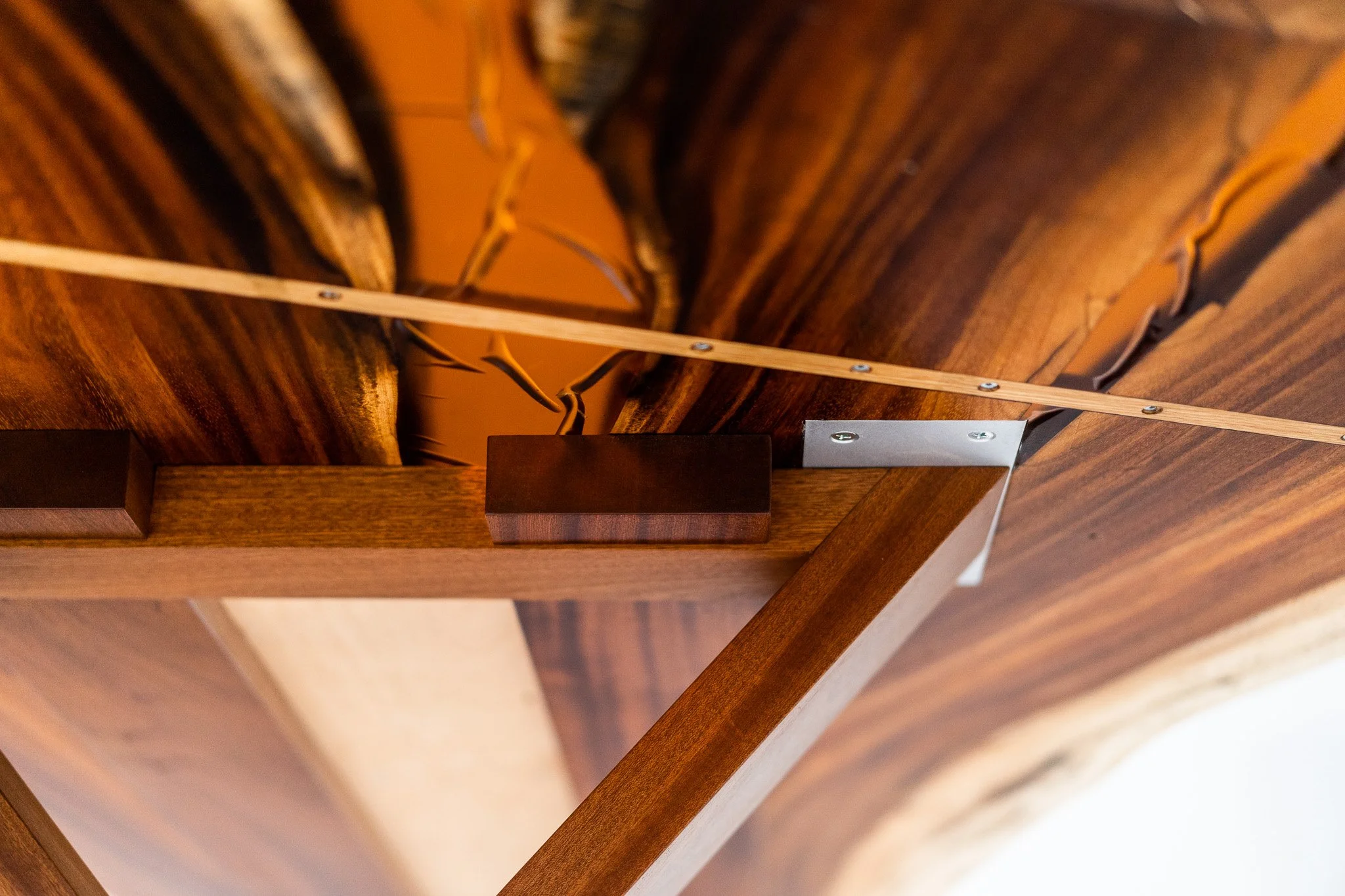 Close-up of wooden furniture with a metal hinge, a wooden support, and an exposed interior with electrical wiring.