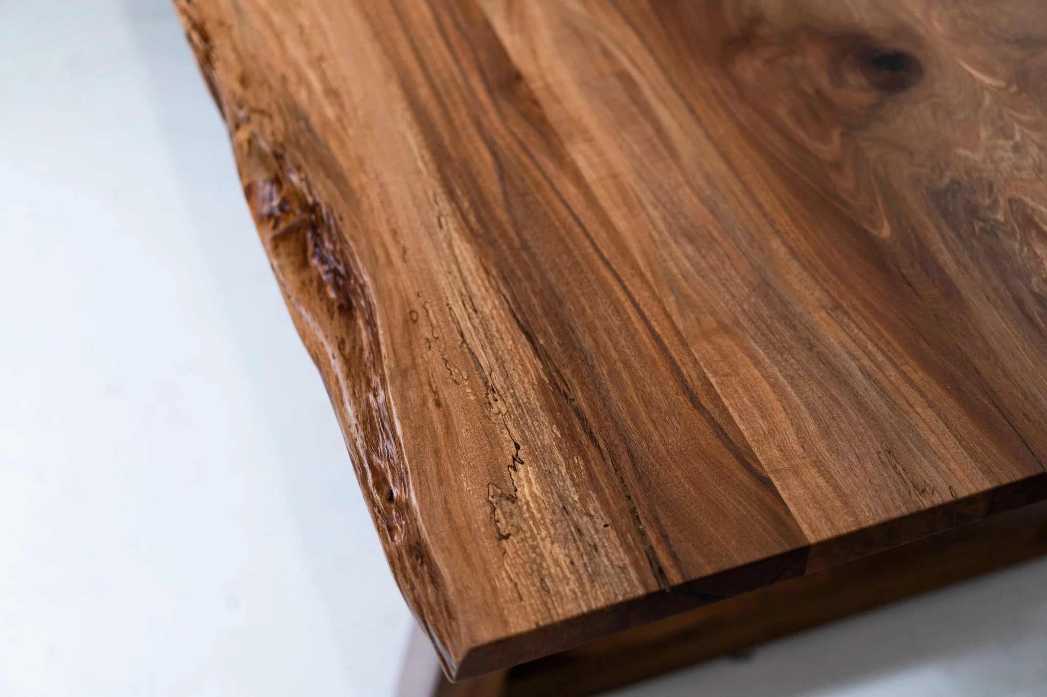 Close-up of a polished wooden surface with natural wood grain patterns and irregular edges.