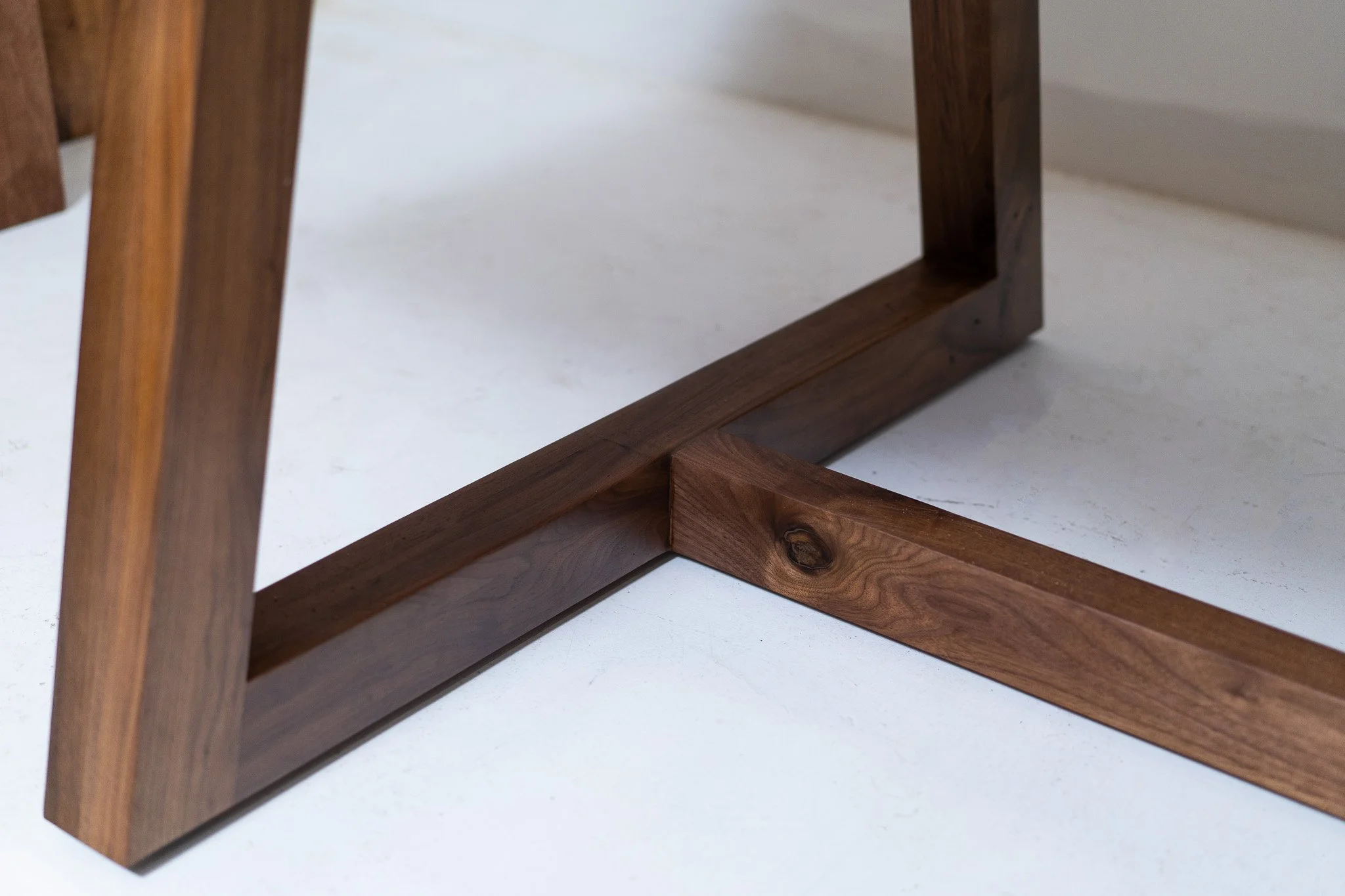 Close-up of a wooden furniture piece with intersecting wooden beams on a white surface.