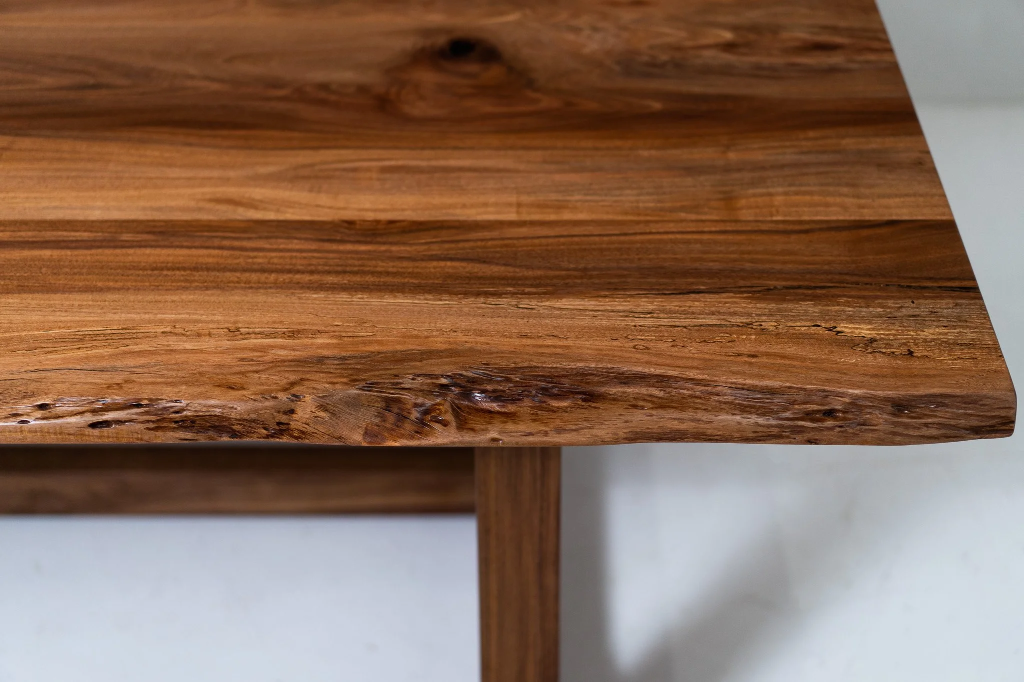 Close-up of a wooden table corner showcasing the wood grain and natural knots.