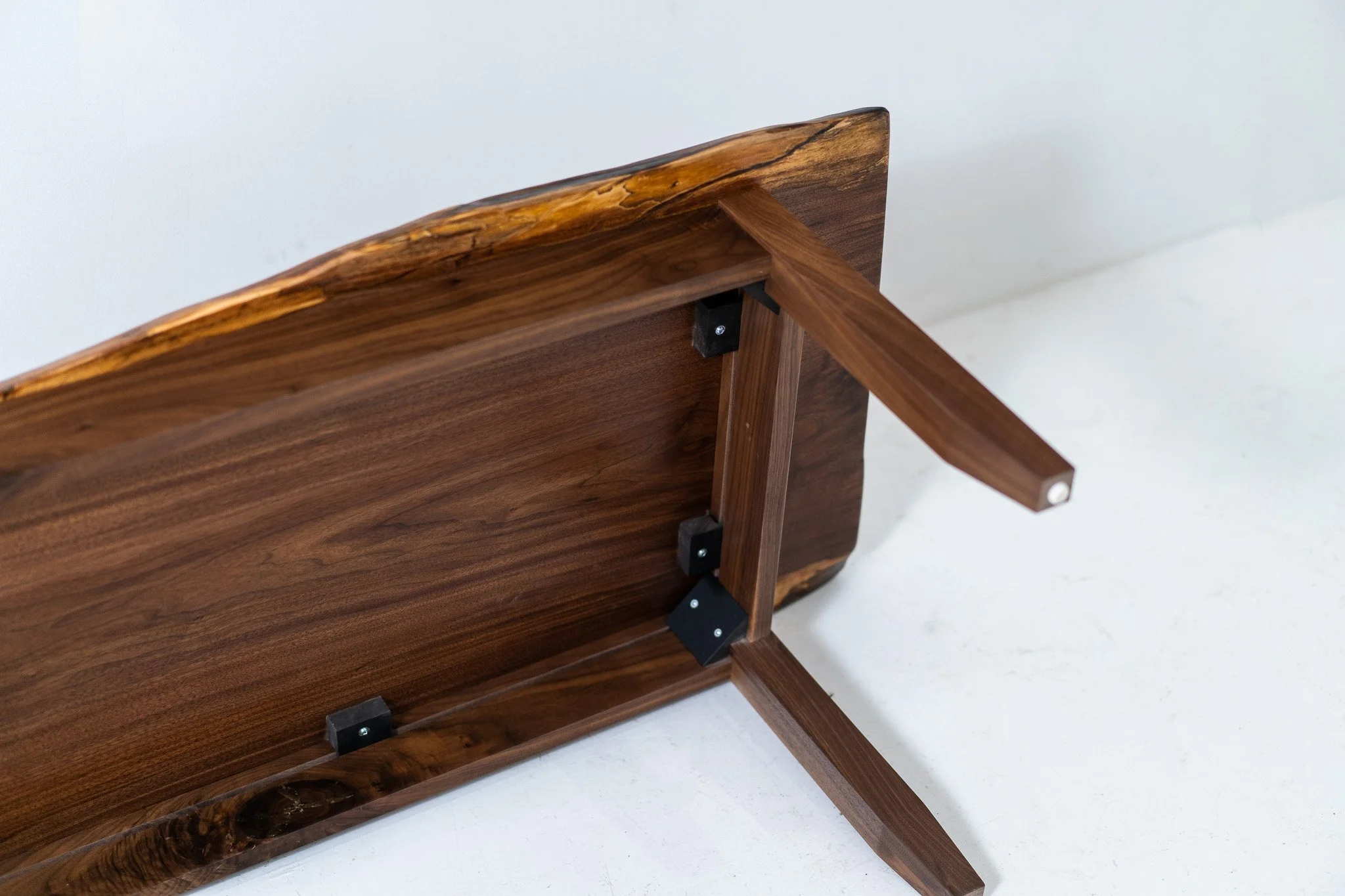 Upside-down wooden table with black metal brackets