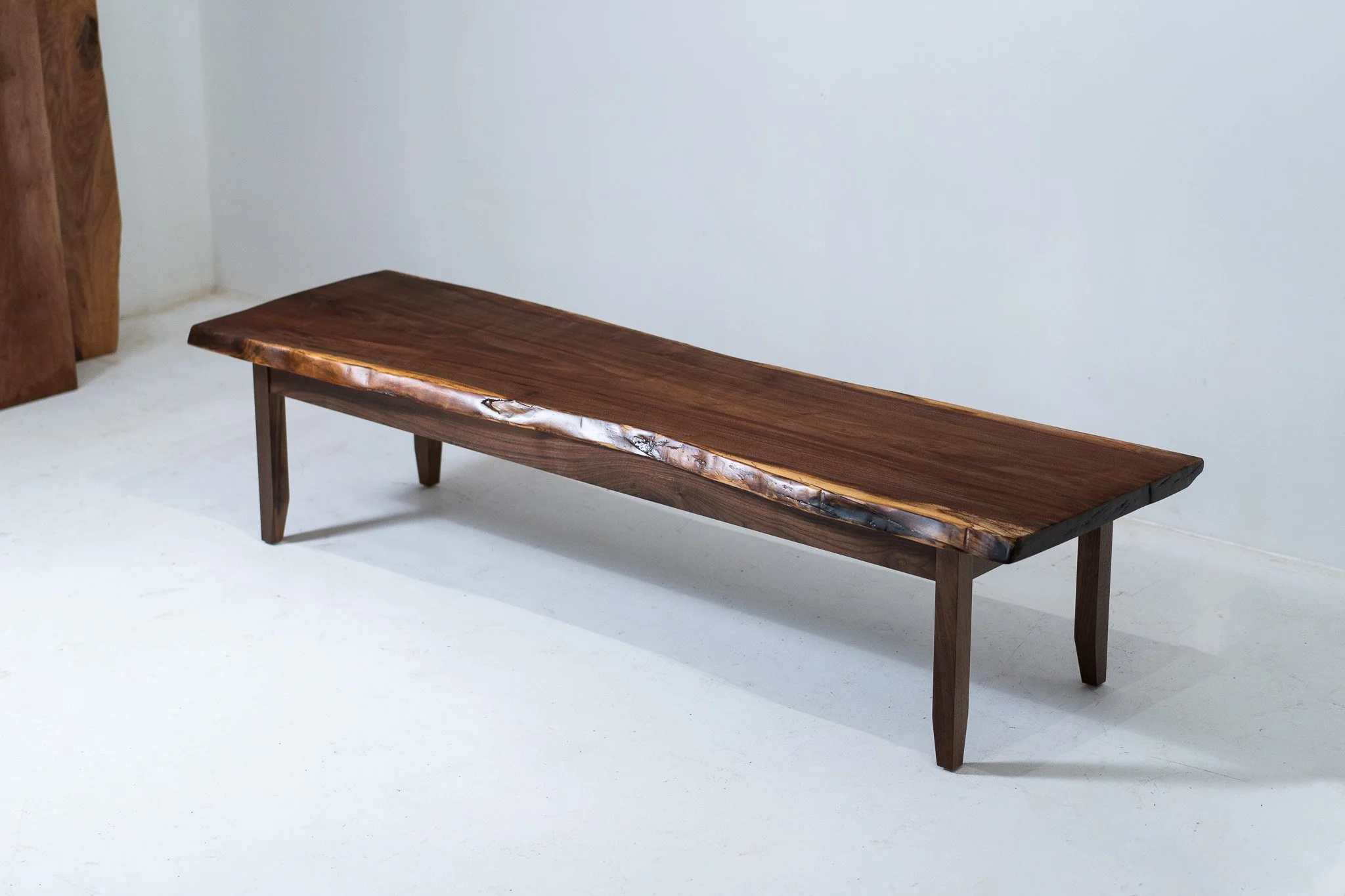 Wooden bench with a natural finish, placed in a white room.