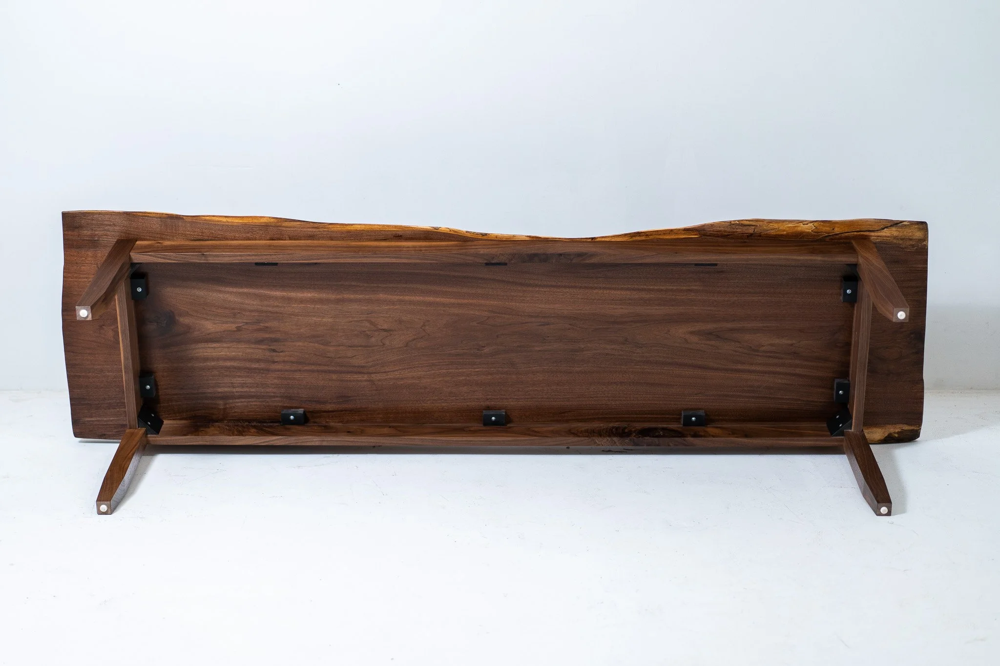 A wooden table with foldable legs upside down showing the underside.