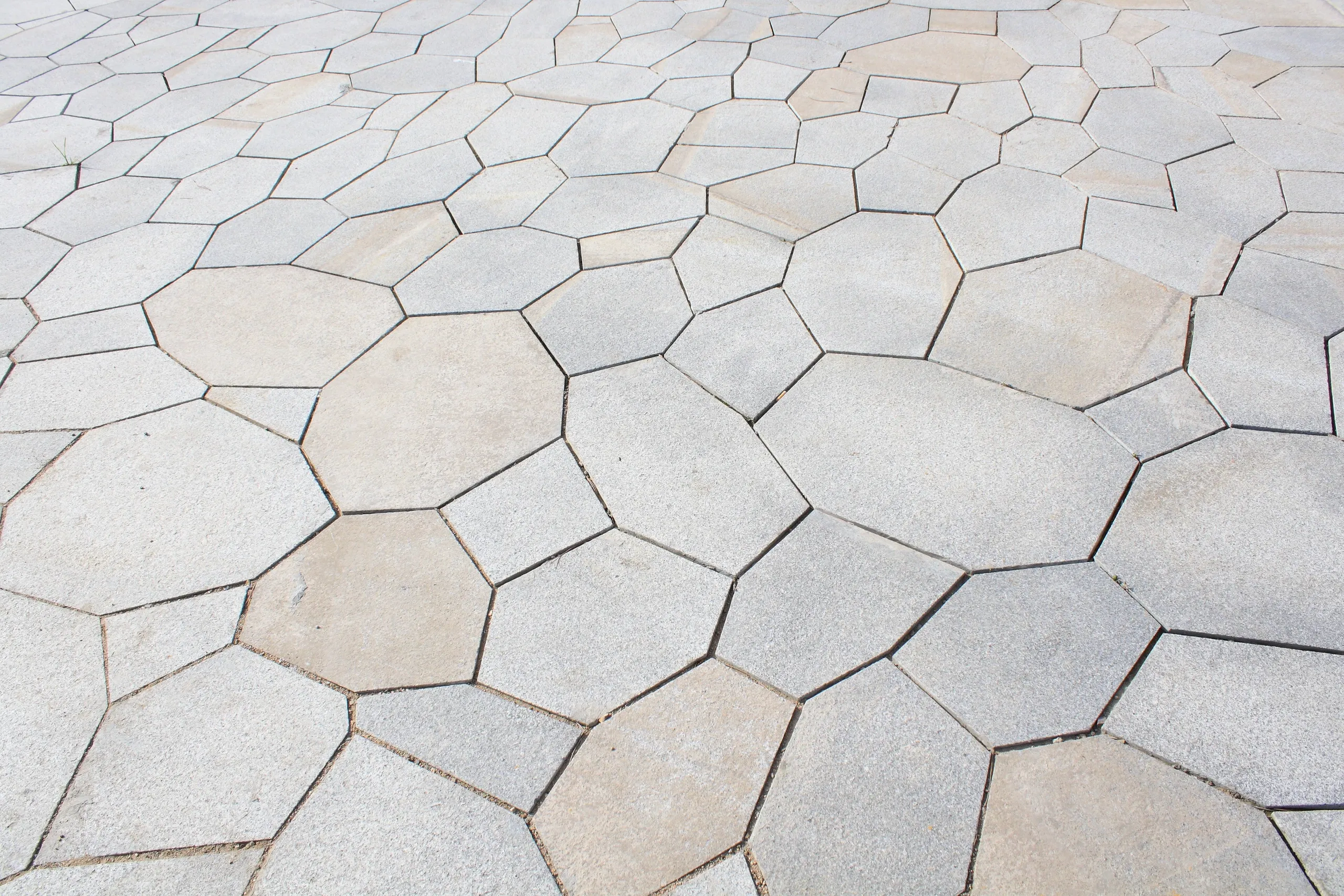 A paved surface made of hexagonal concrete tiles in light beige and gray shades.