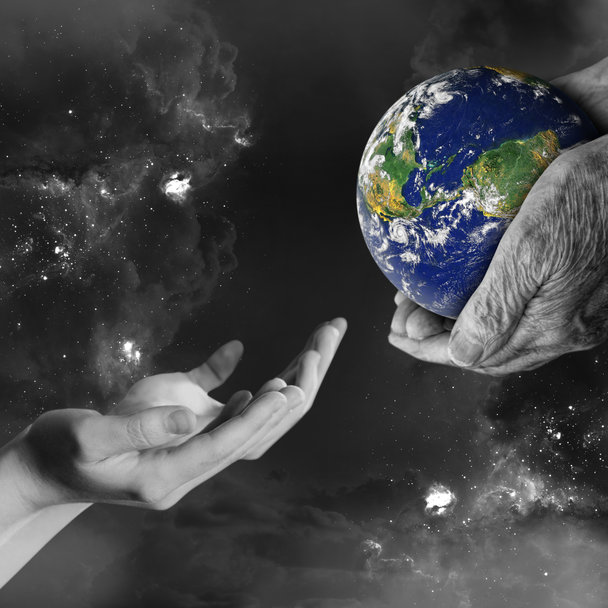 A black and white hand holding a colorful planet Earth in space, with a hand below reaching out.
