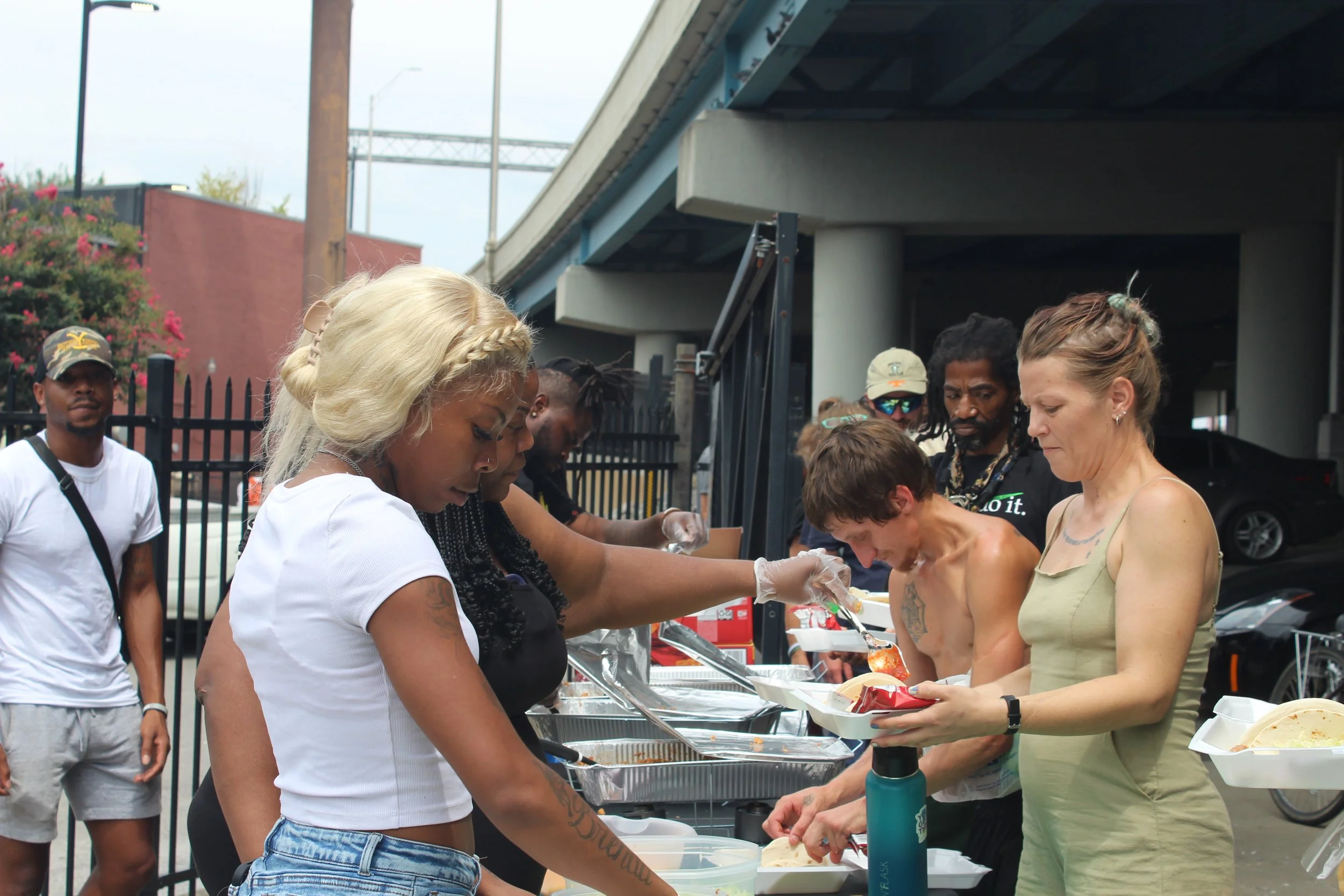 People serving and receiving food at an outdoor community event.