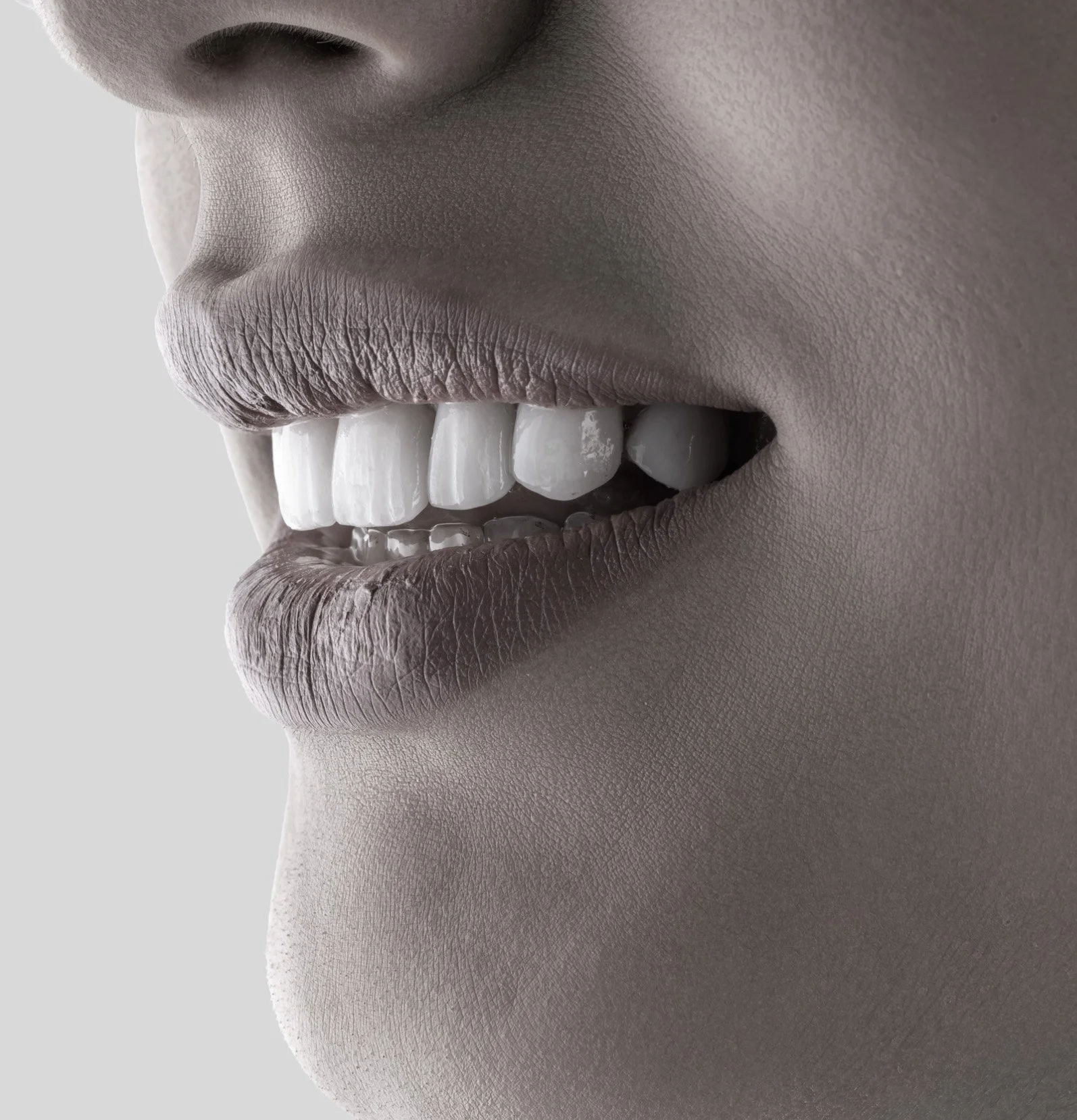 Close-up of a person's lips and teeth, with skin in grayscale.