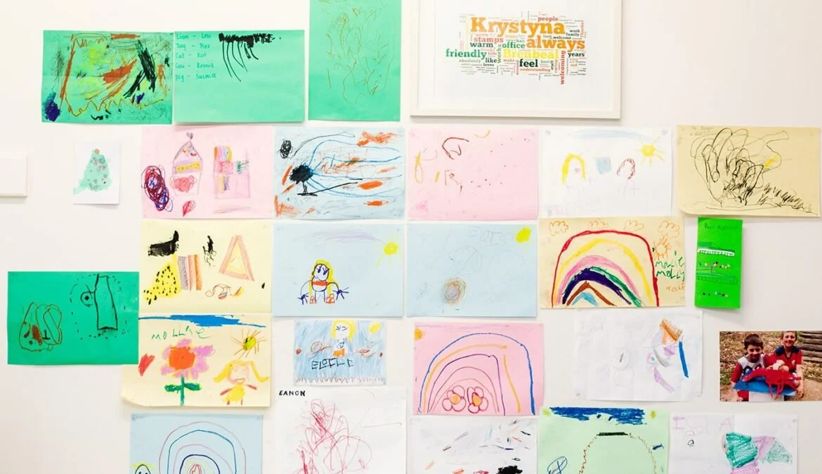 Children's colorful drawings and a photo of two kids outdoors on a bulletin board.