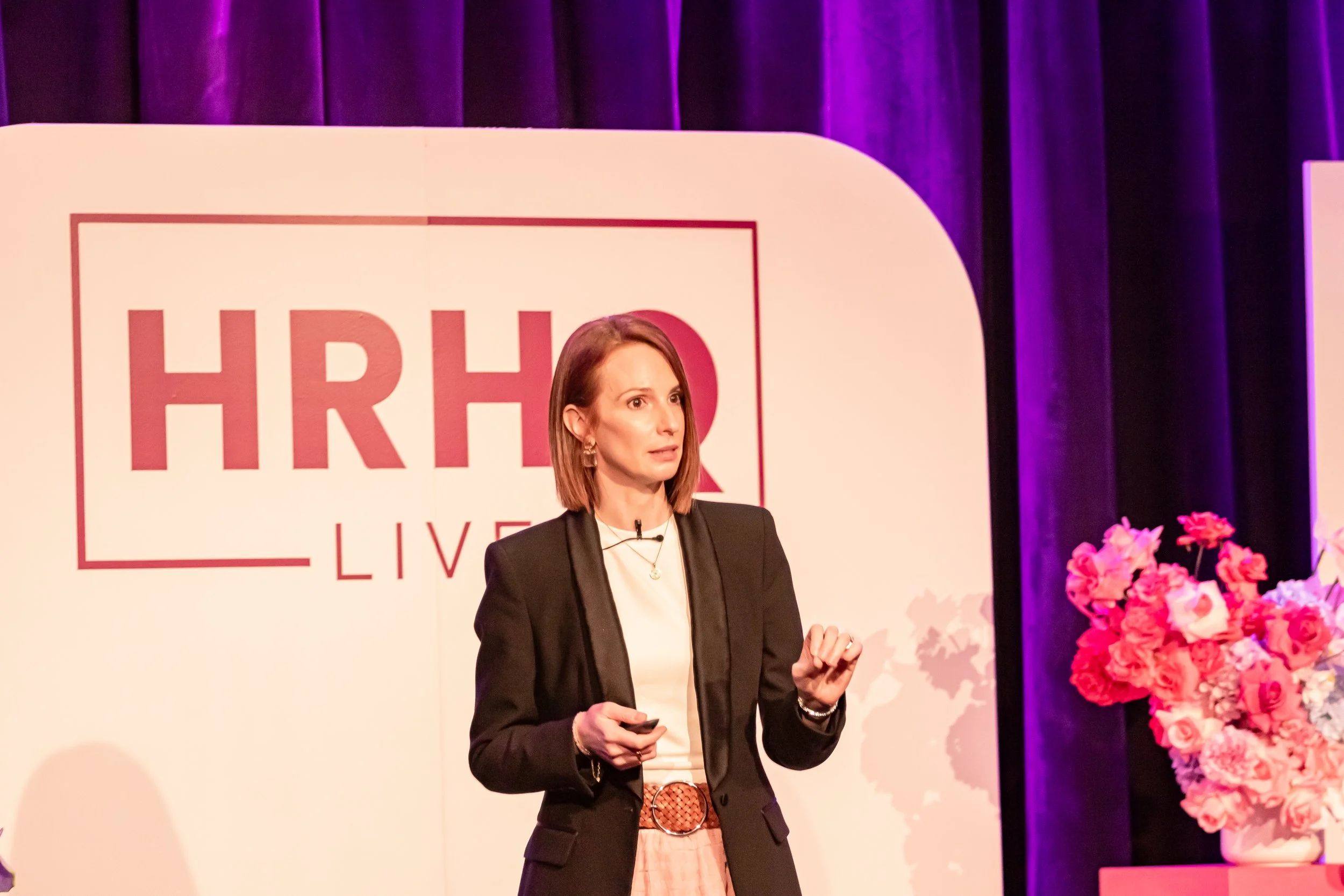 Conference flyer for HRHQ Live event showcasing a smiling woman in a white shirt with a city skyline background. The event is scheduled for July 31st from 9AM to 6:30PM at Trusts Arena in Auckland. The flyer has text promoting the conference for HR professionals.