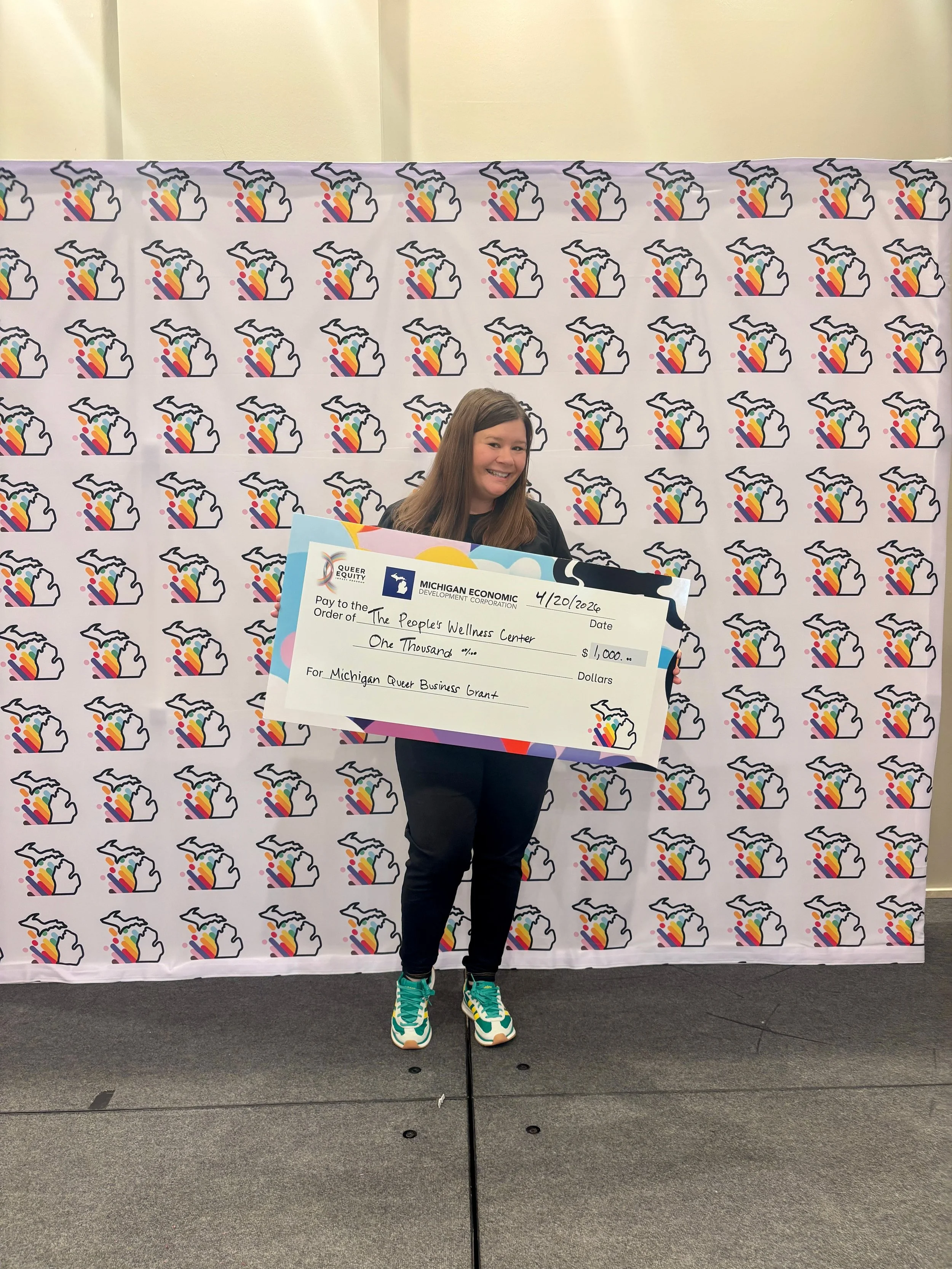 Rachele Rose holding a grant check from the Michigan Economic Development Corporation