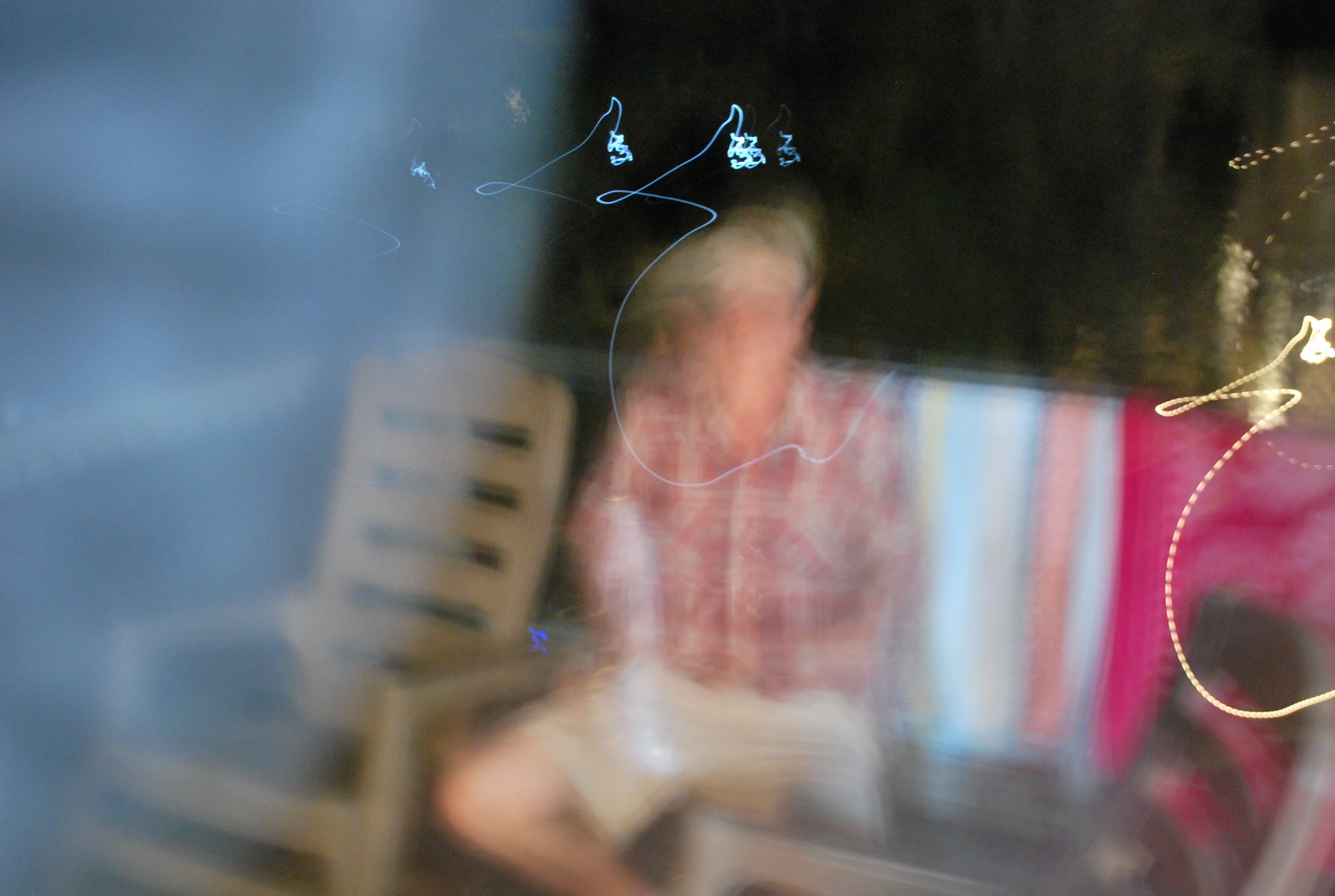 Blurry photo of a person in a red plaid shirt, at what appears to be a restaurant or cafe, with various lights and objects around.