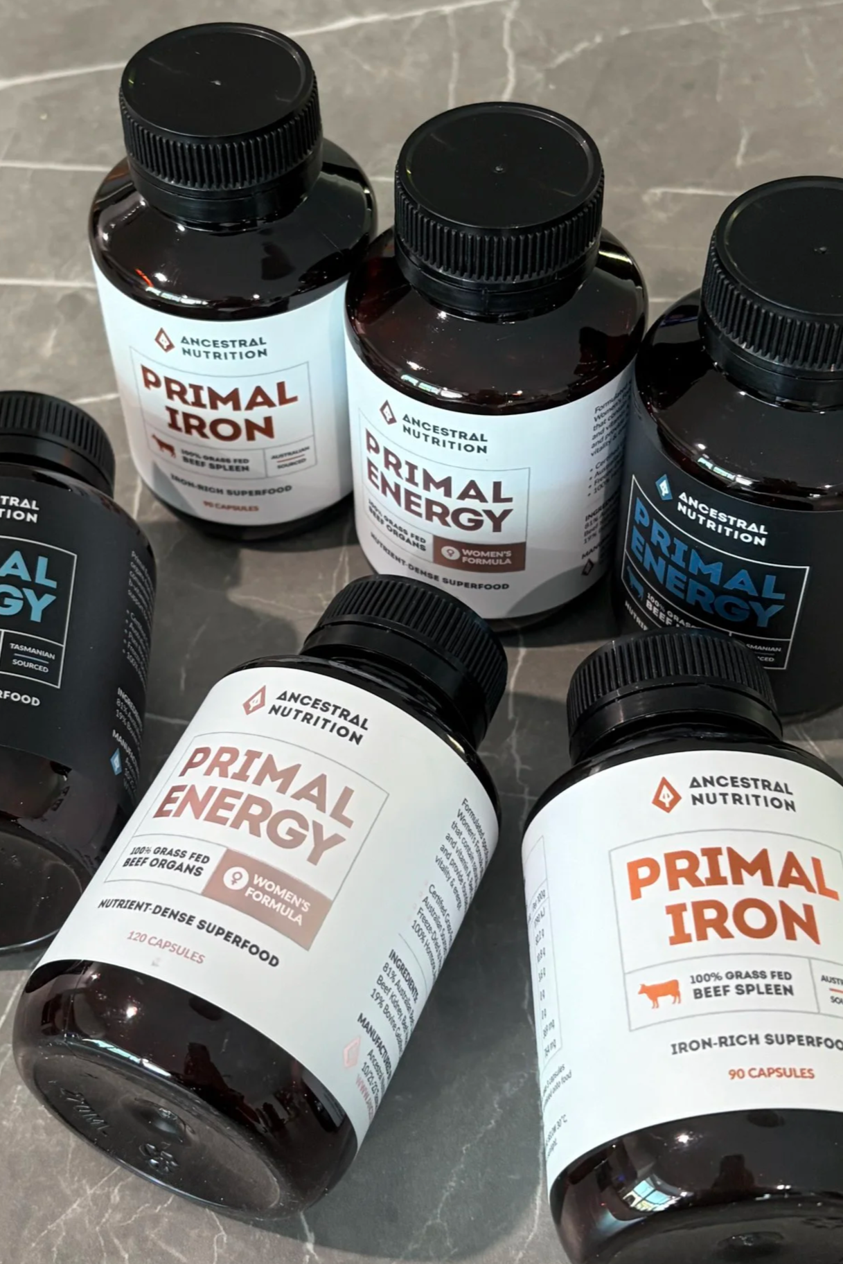 Bottles of Ancestral Nutrition Primal Energy and Primal Iron supplements on a gray surface.