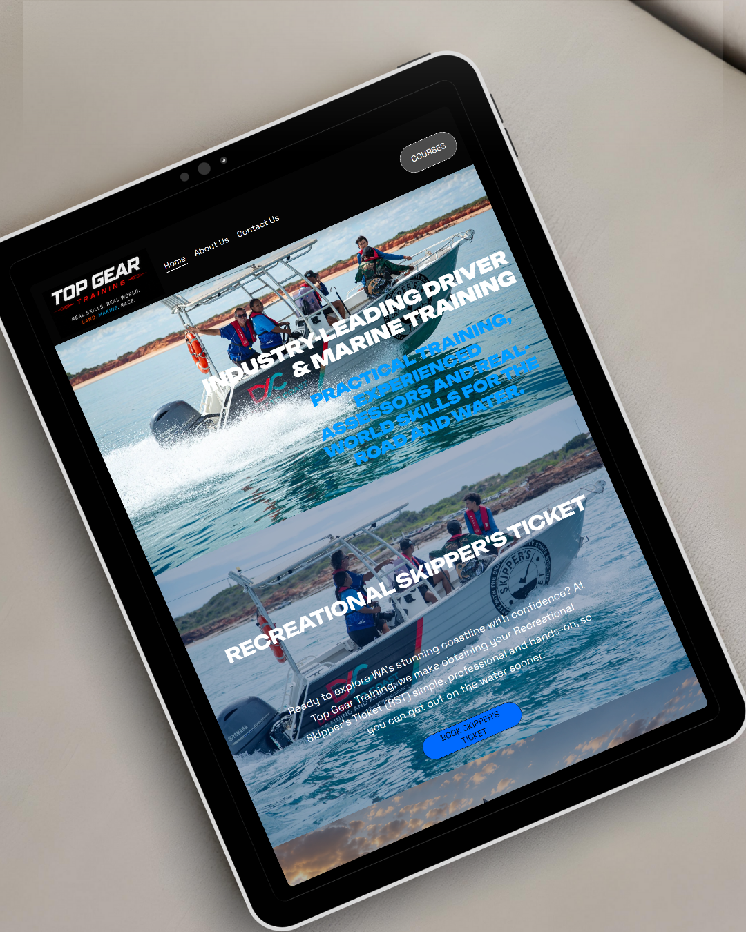 Tablet displaying a website for Top Gear Training, featuring images of a boat with people in life jackets. The site promotes industry-leading driving and marine training, and offers information about recreational skipper's tickets.