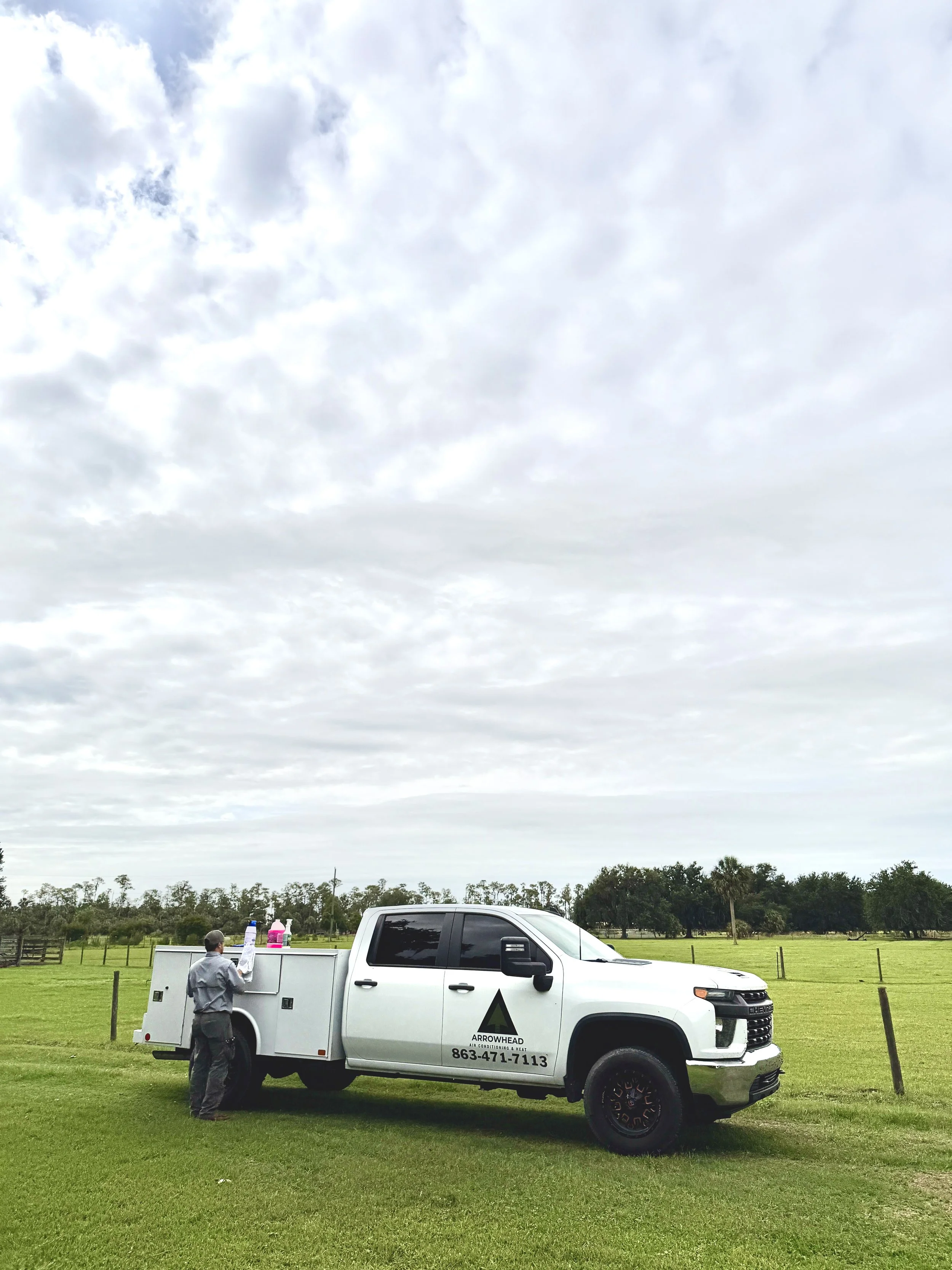 Arrowhead AC technician working from a branded service truck on a residential property, preparing equipment for air conditioning repair, HVAC maintenance, or heating service in a rural Florida setting.