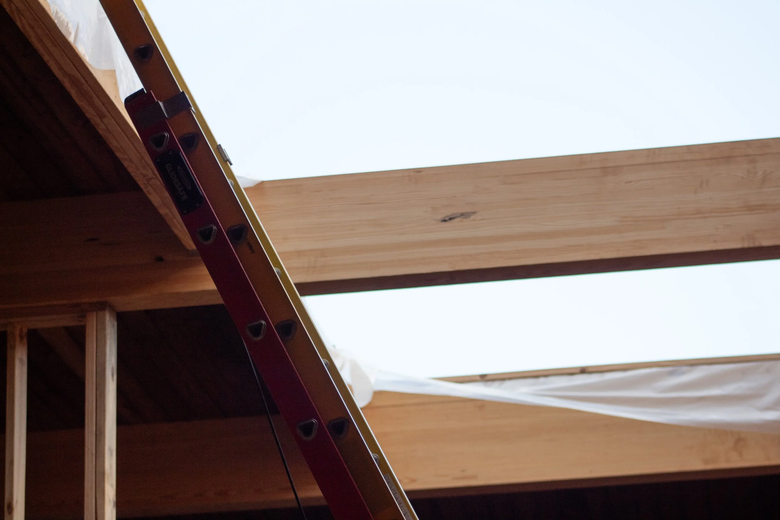 wooden roof beams under construction with a ladder leaning against them.