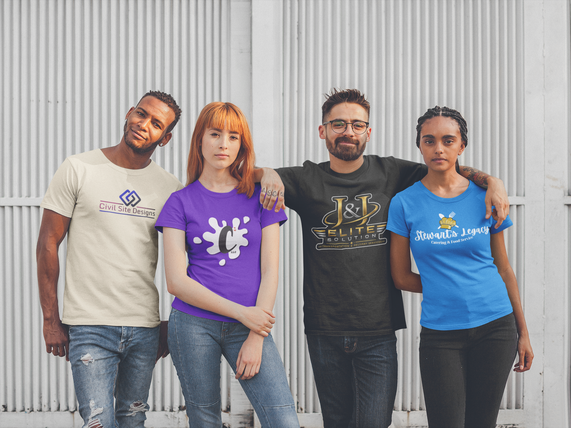 A diverse group of four young adults standing together in front of a metal wall, posing for a photo with their arms around each other, wearing casual t-shirts with various logos.