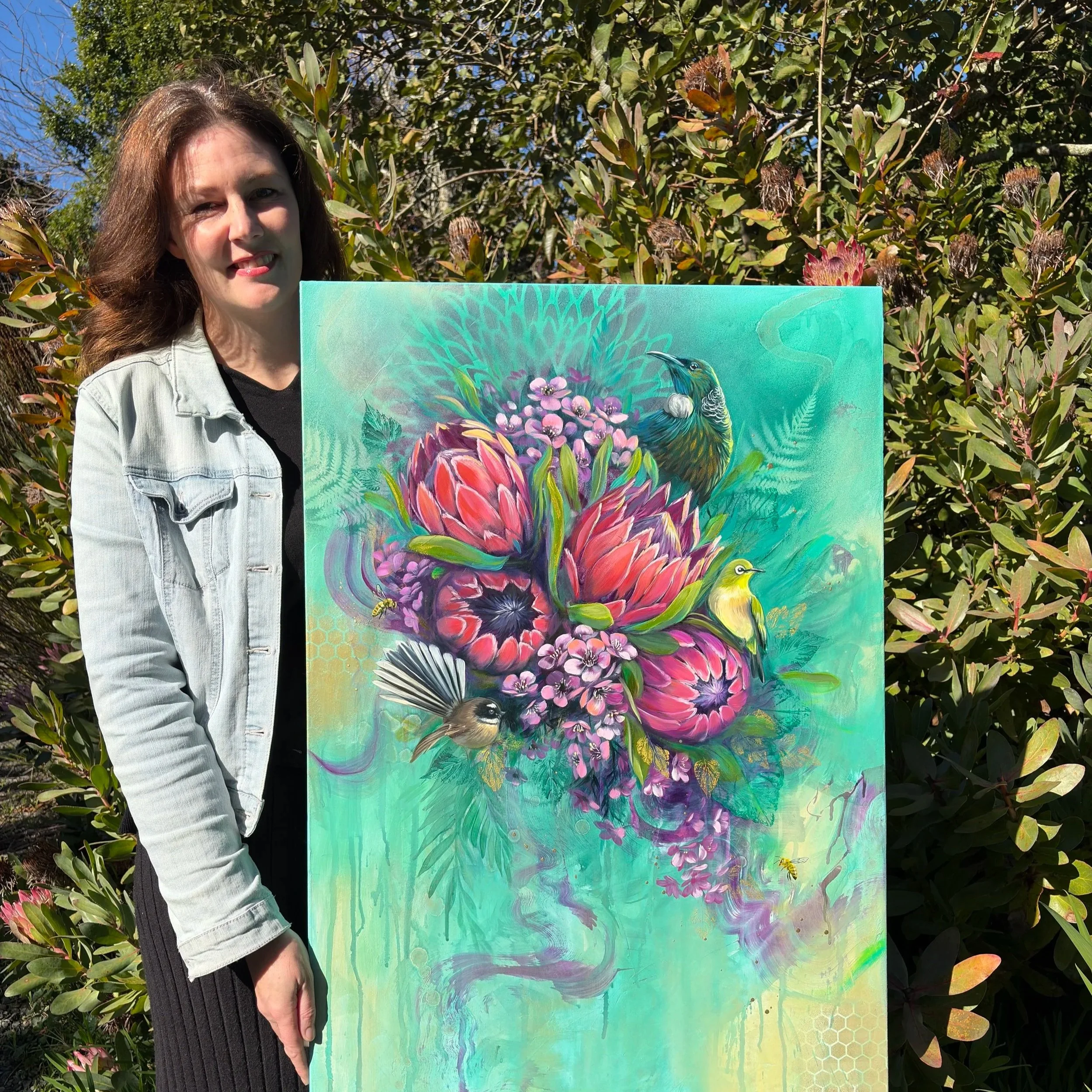 New Zealand artist Jessica Jane Holliday with an original native bird and floral painting featuring proteas, a tūī, fantail and silvereye