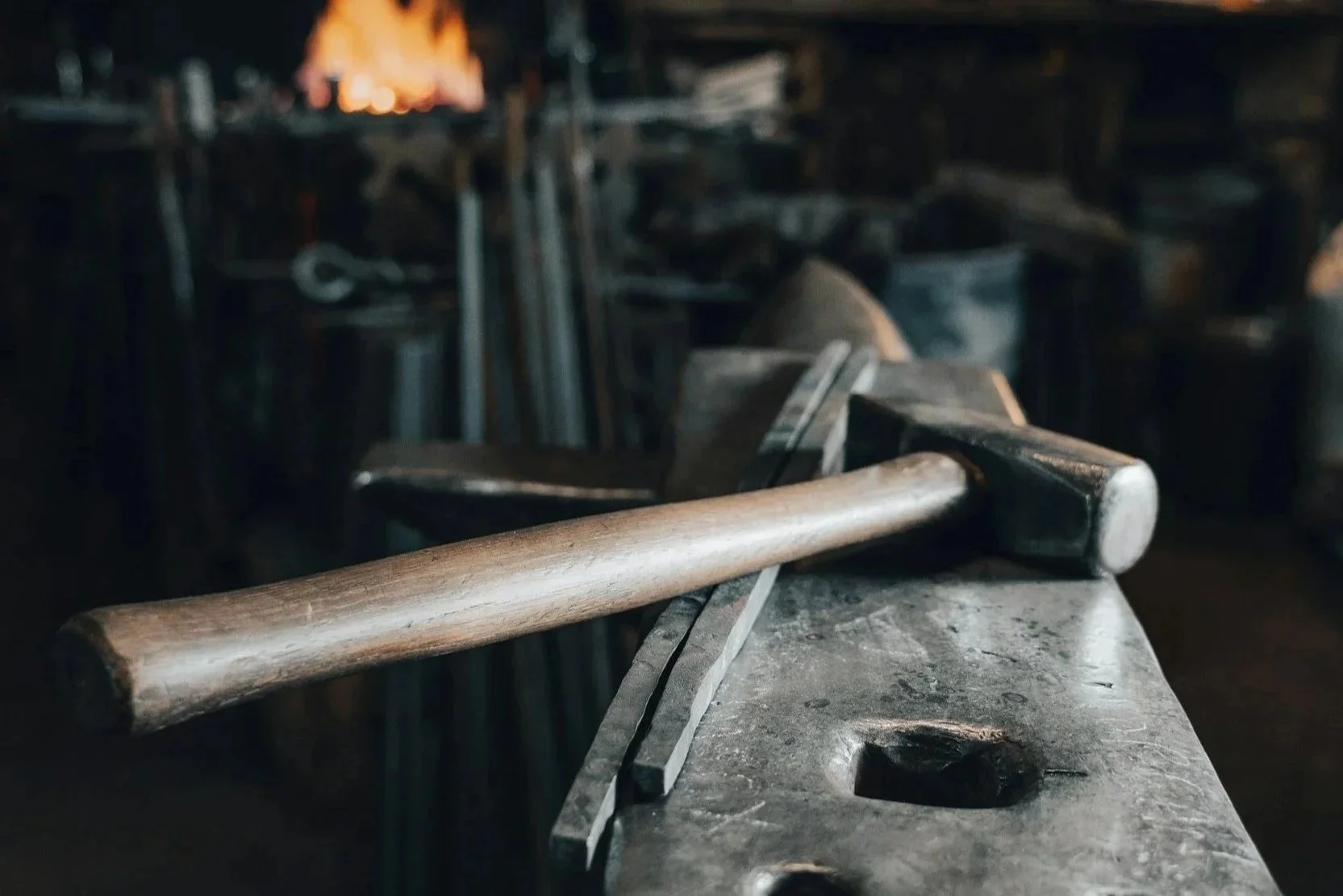 A blacksmith's workbench with a hammer resting on it, in a dimly lit forge or blacksmith's workshop.