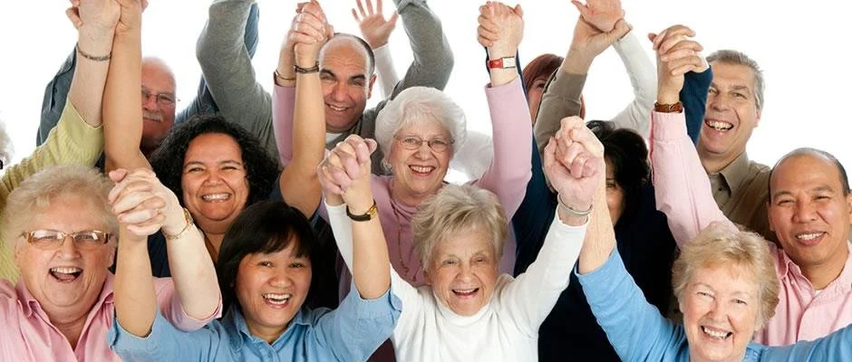 A large group of diverse, elderly people smiling and celebrating with raised hands. TriCity Action Society. 