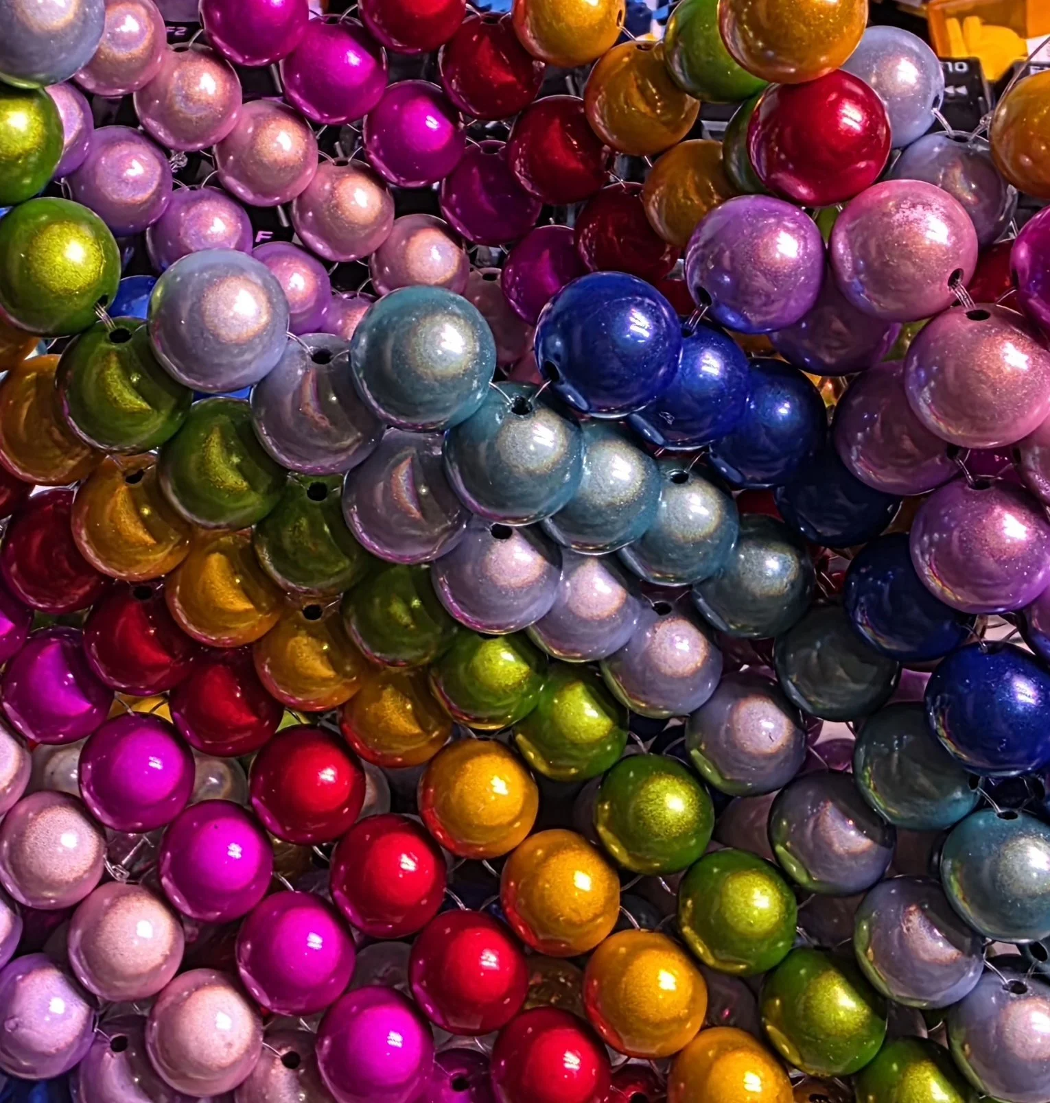 Close-up of colorful shiny Christmas ornament balls in pink, purple, blue, green, orange, yellow, and red.