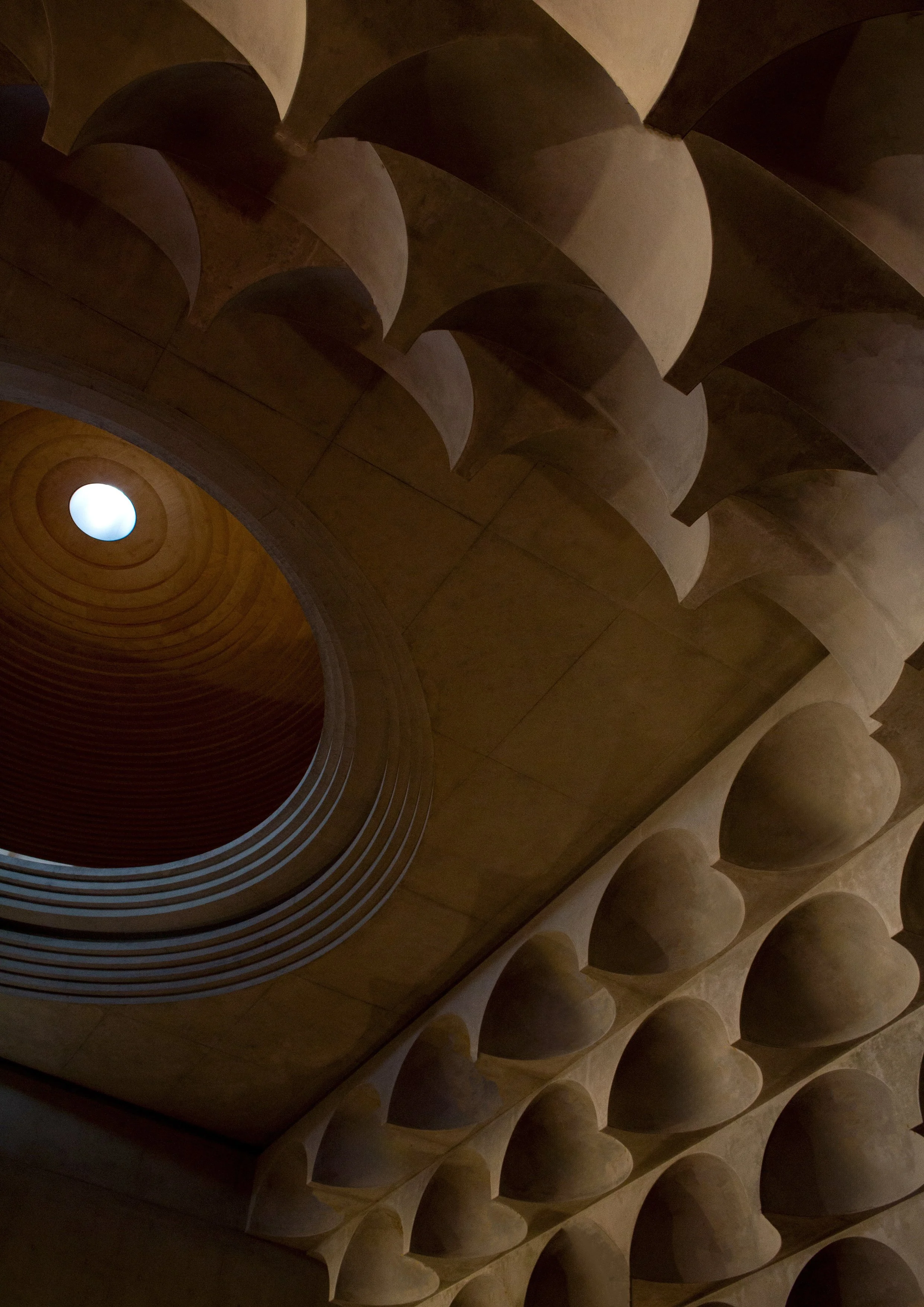 Interior view of a building with a circular skylight and architectural dome-shaped ceiling structures.