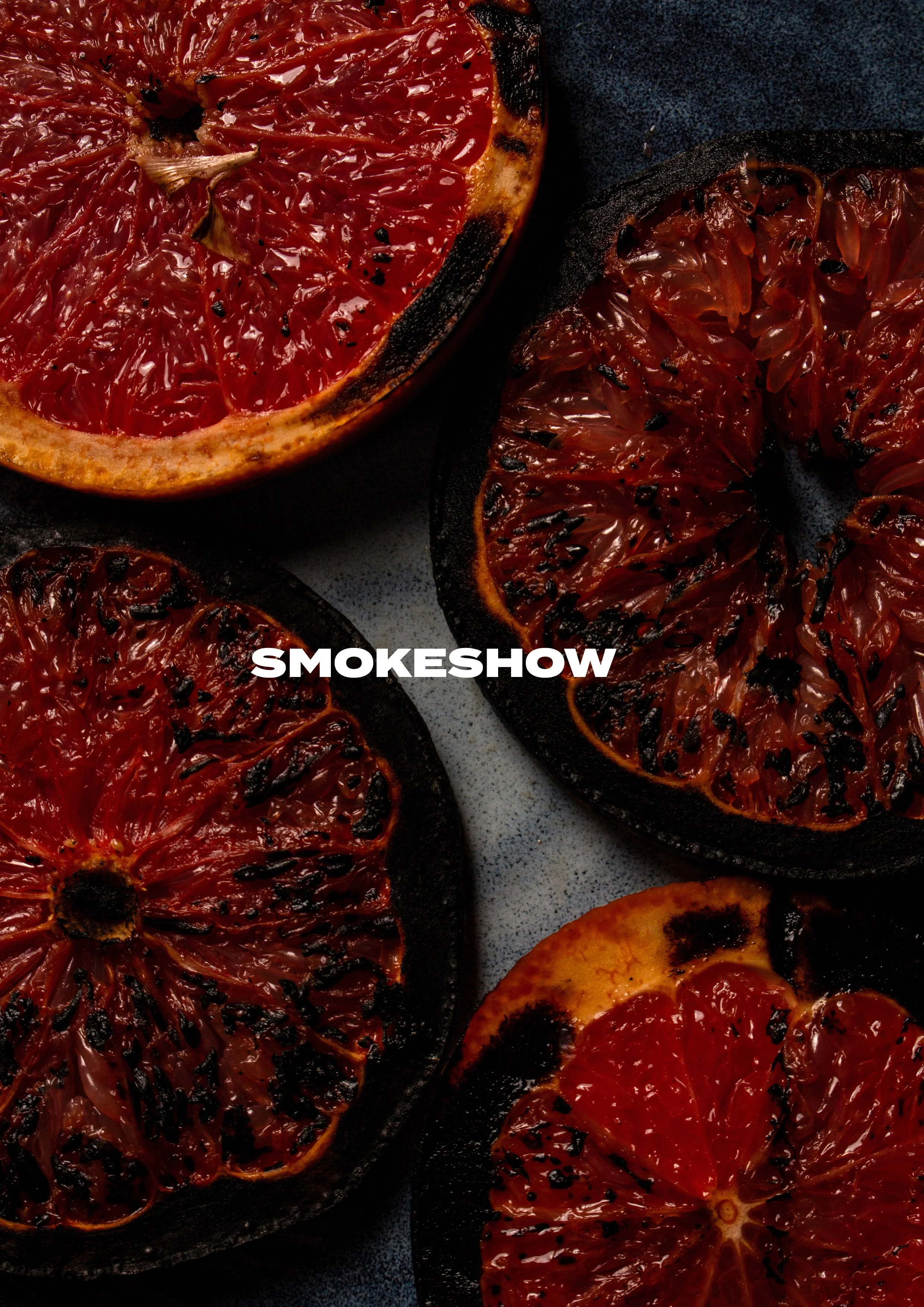 Charred blood orange slices on a dark background with the word 'SMOKESHOW' in white text