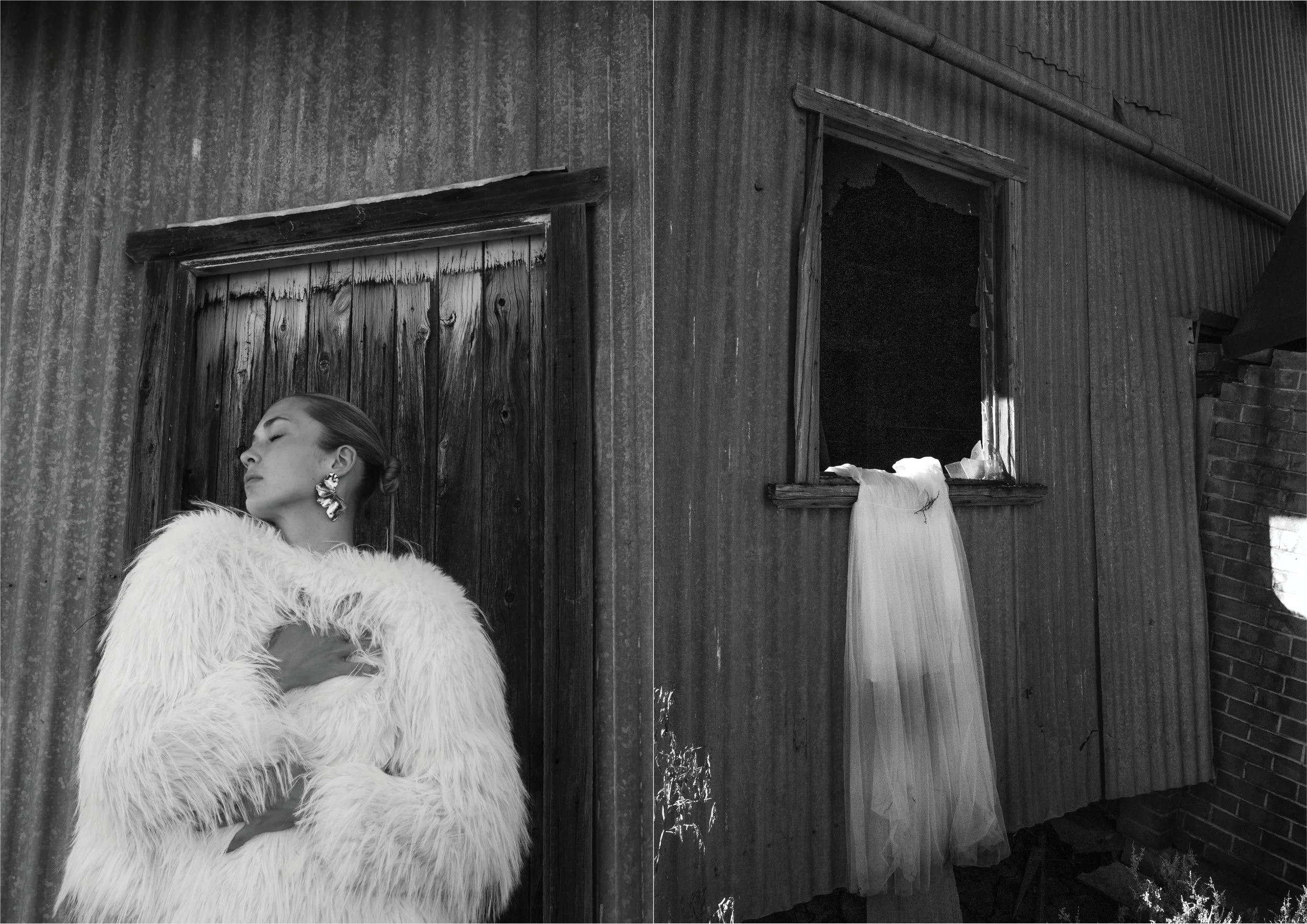 A woman with her eyes closed, wearing a fluffy white coat and large earrings, stands against a weathered wooden door on a rustic building, with a tattered wedding dress hanging from a window on the side of the building.