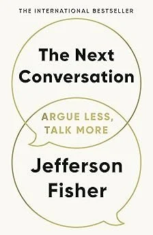 Book cover titled 'The Next Conversation' by Jefferson Fisher with the subtitle 'Argue Less, Talk More' and a circular design.