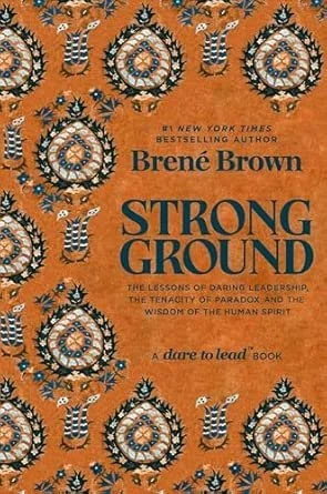 Book cover of 'Strong Ground' by Brené Brown, orange background with black and white circular and striped designs, featuring the title, author's name, and subtitle about leadership and human spirit.