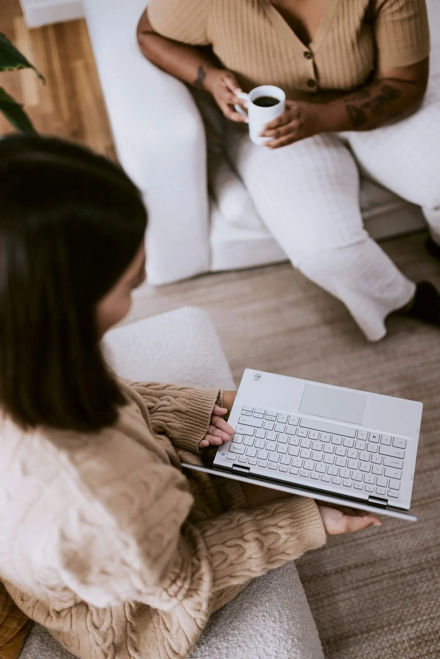 Two colleagues in a relaxed conversation, one with a laptop and one holding a coffee cup — reflecting the empathic communication style at the heart of Clara's team communication training