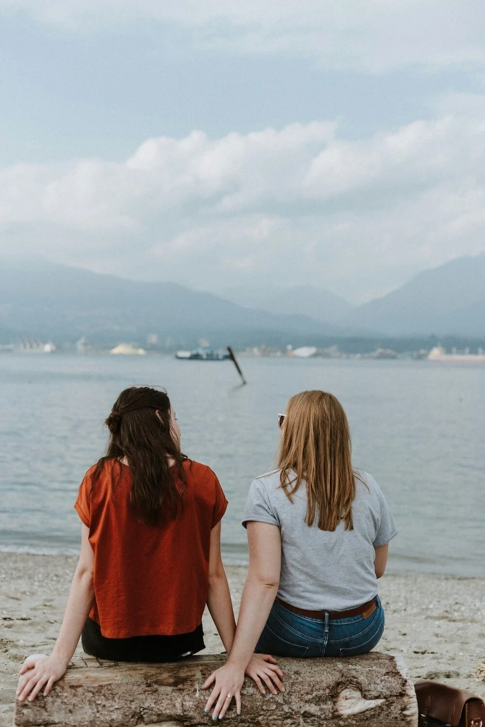 Two women looking out at the ocean engaged in open, connected dialogue — the kind of exchange at the heart of NVC training
