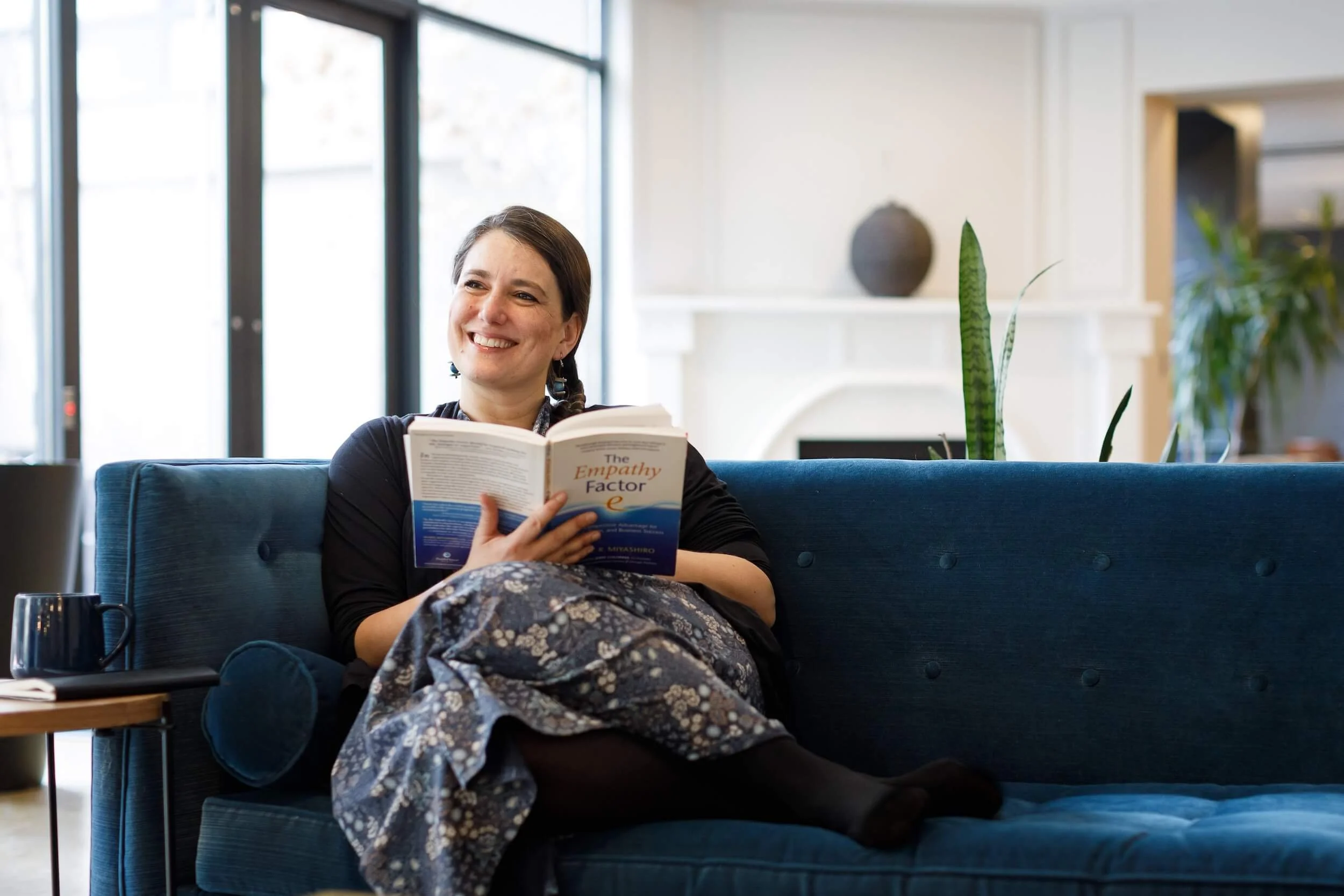 Clara Moisello seated on a comfortable couch reading The Empathy Factor