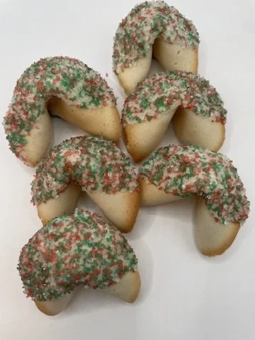 Six crescent-shaped cookies with green and red sprinkles on top