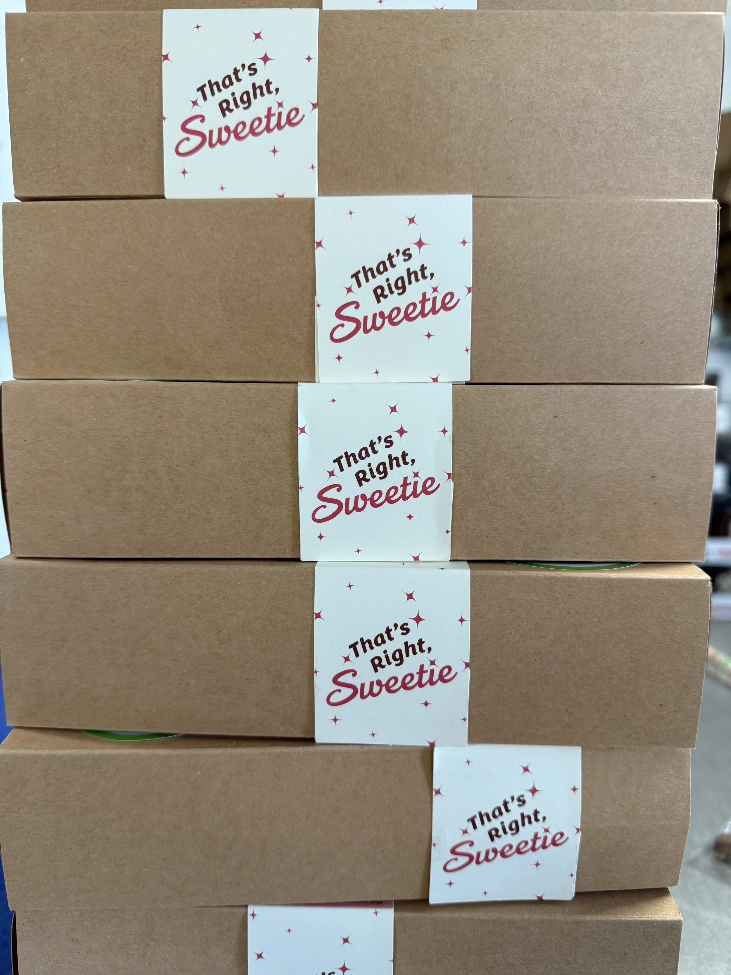 Stacked to ship are 1/2 dozen packaged chocolate-dipped pretzel rods in kraft cardboard boxes with labels that read 'That's Right, Sweetie' branding.
