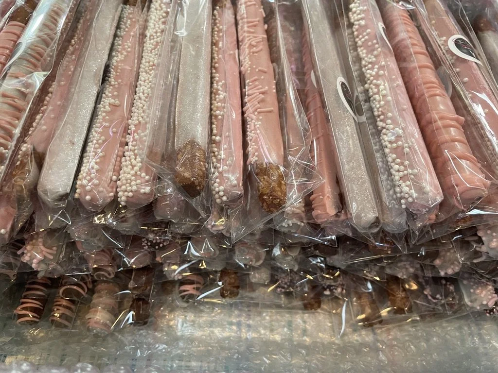 Pink and brown decorated cookies wrapped in clear plastic packaging, arranged in rows.