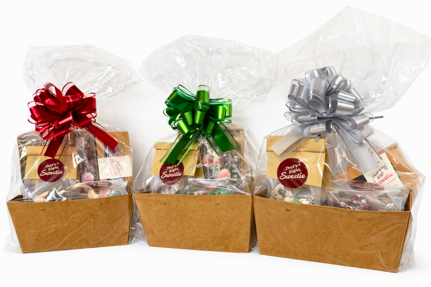 Gift baskets wrapped in clear plastic with large colorful bows, containing various treats and snacks.