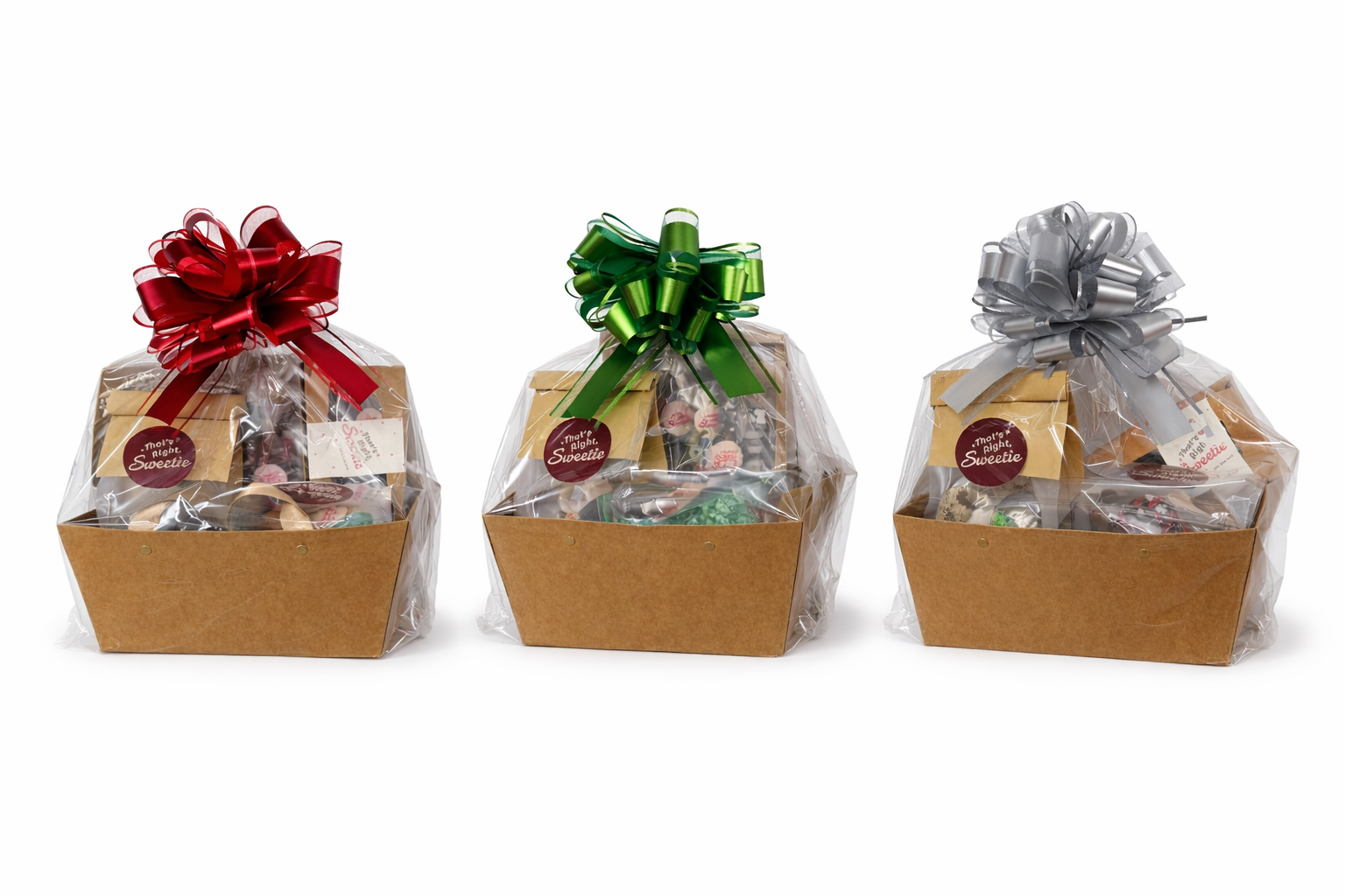 Three gift baskets wrapped in clear cellophane with colorful bows (red, green, and silver) on top.