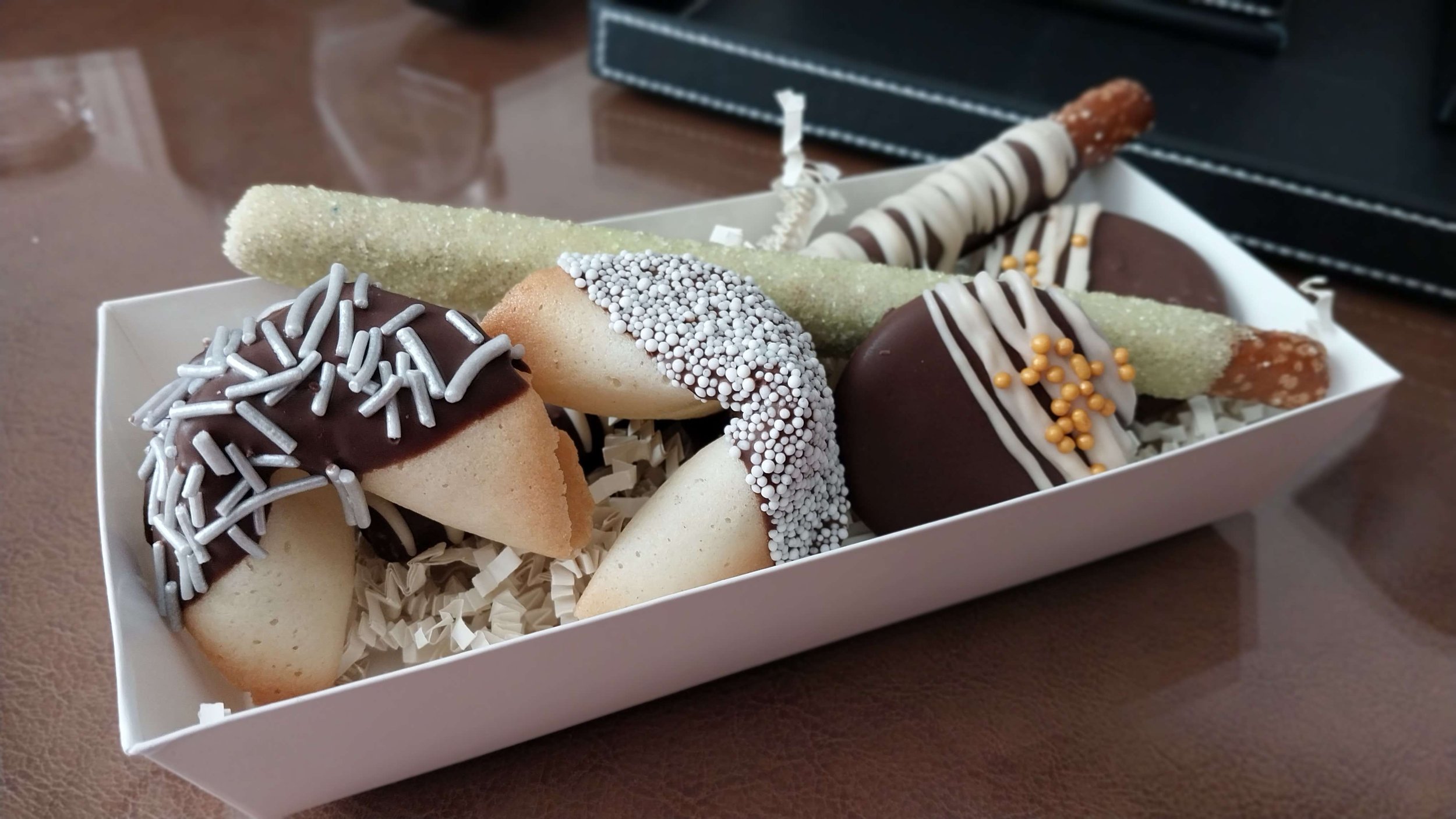 A white box of assorted decorated marshmallow candies on a wooden table.
