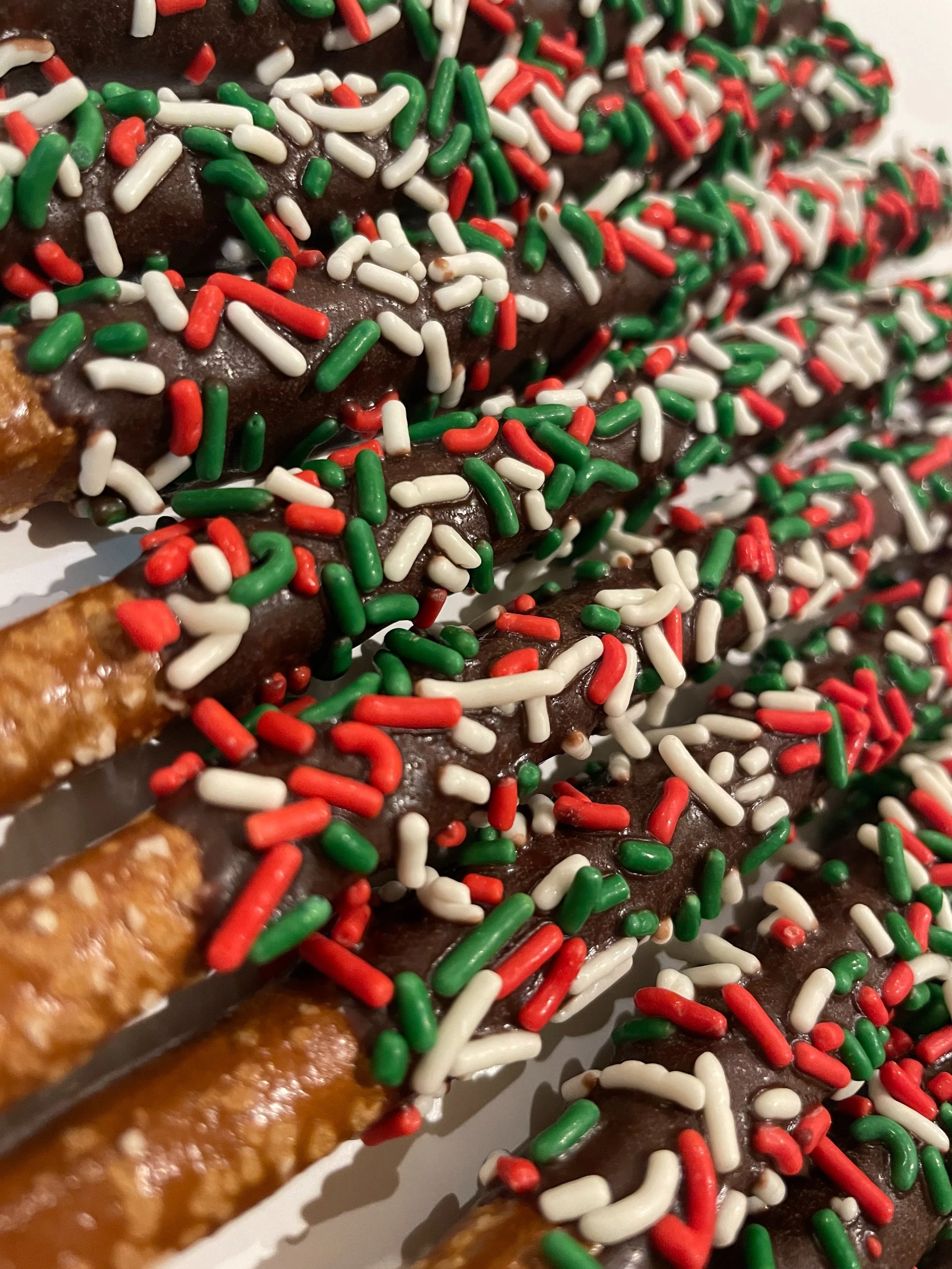Close-up of an ice cream cone with chocolate topping, colorful red, green, and white sprinkles.