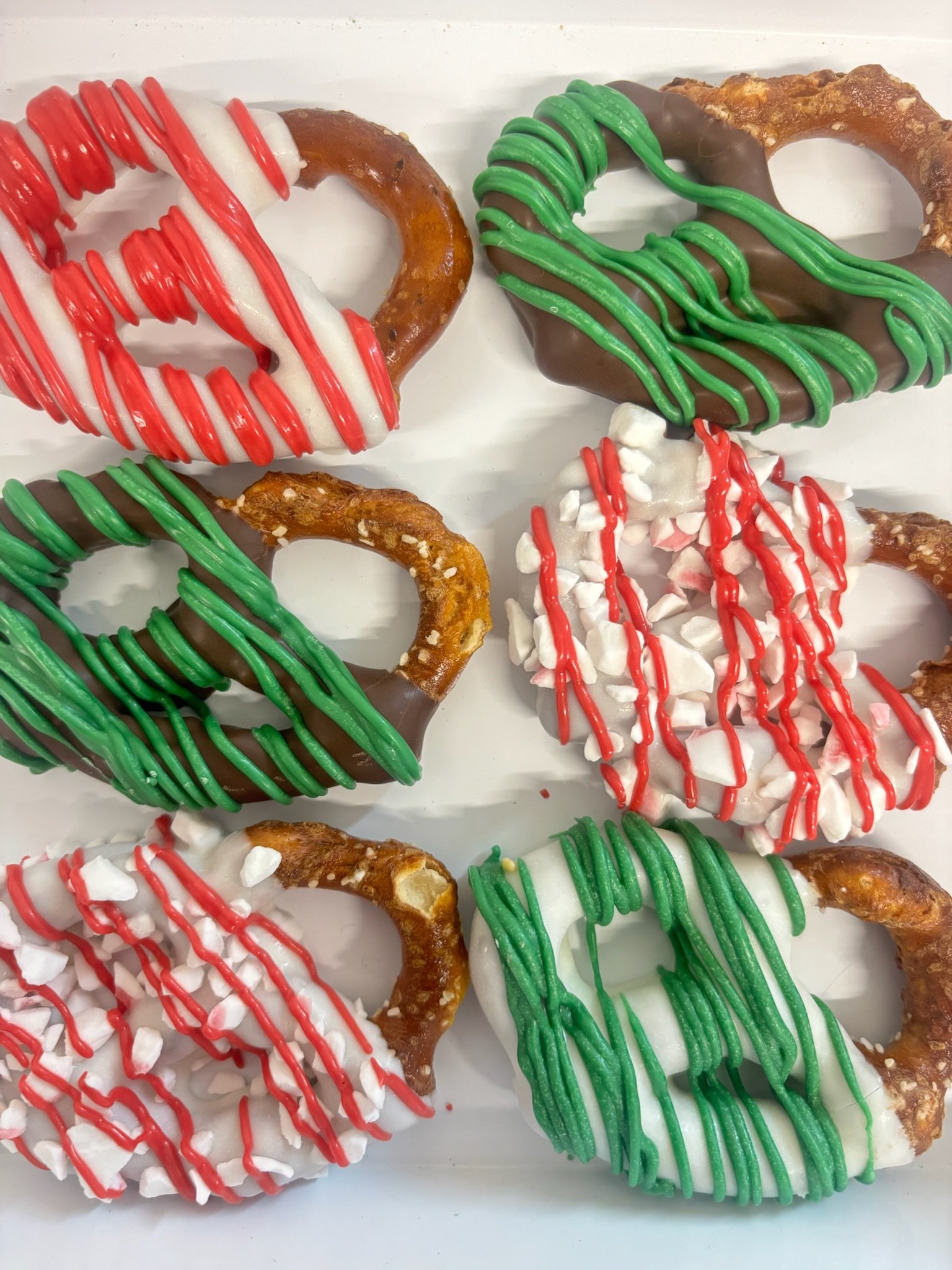 Decorated pretzels with white, red, and green holiday colors and sprinkles.