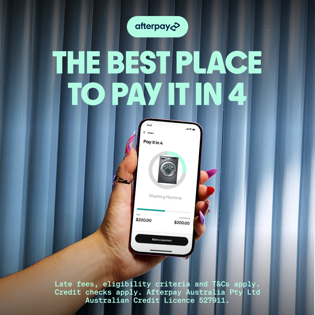 Hand holding smartphone displaying Afterpay payment options for a washing machine with a background of vertical light blue curtains.