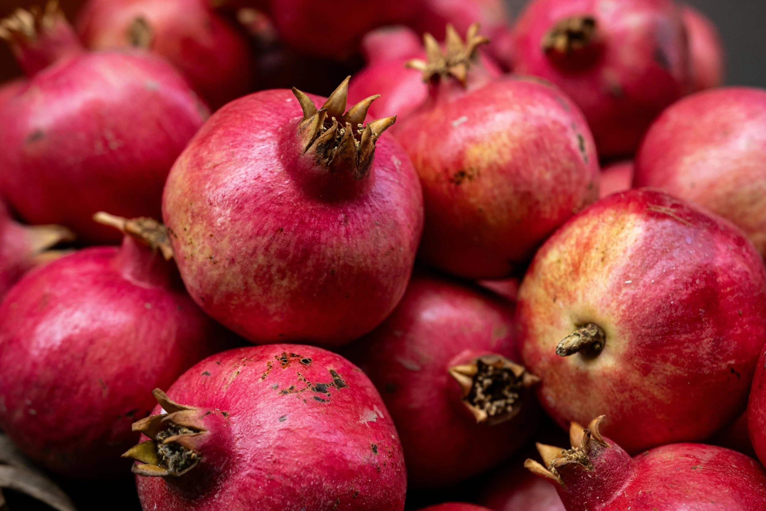 Close-up of fresh pomegranates with pinkish-red skin.