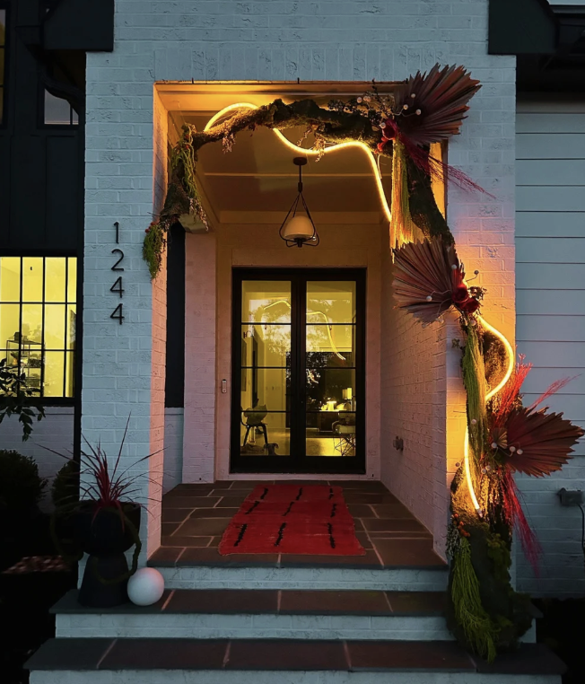 Entryway decorated with floral arrangements and neon lighting, featuring a black door