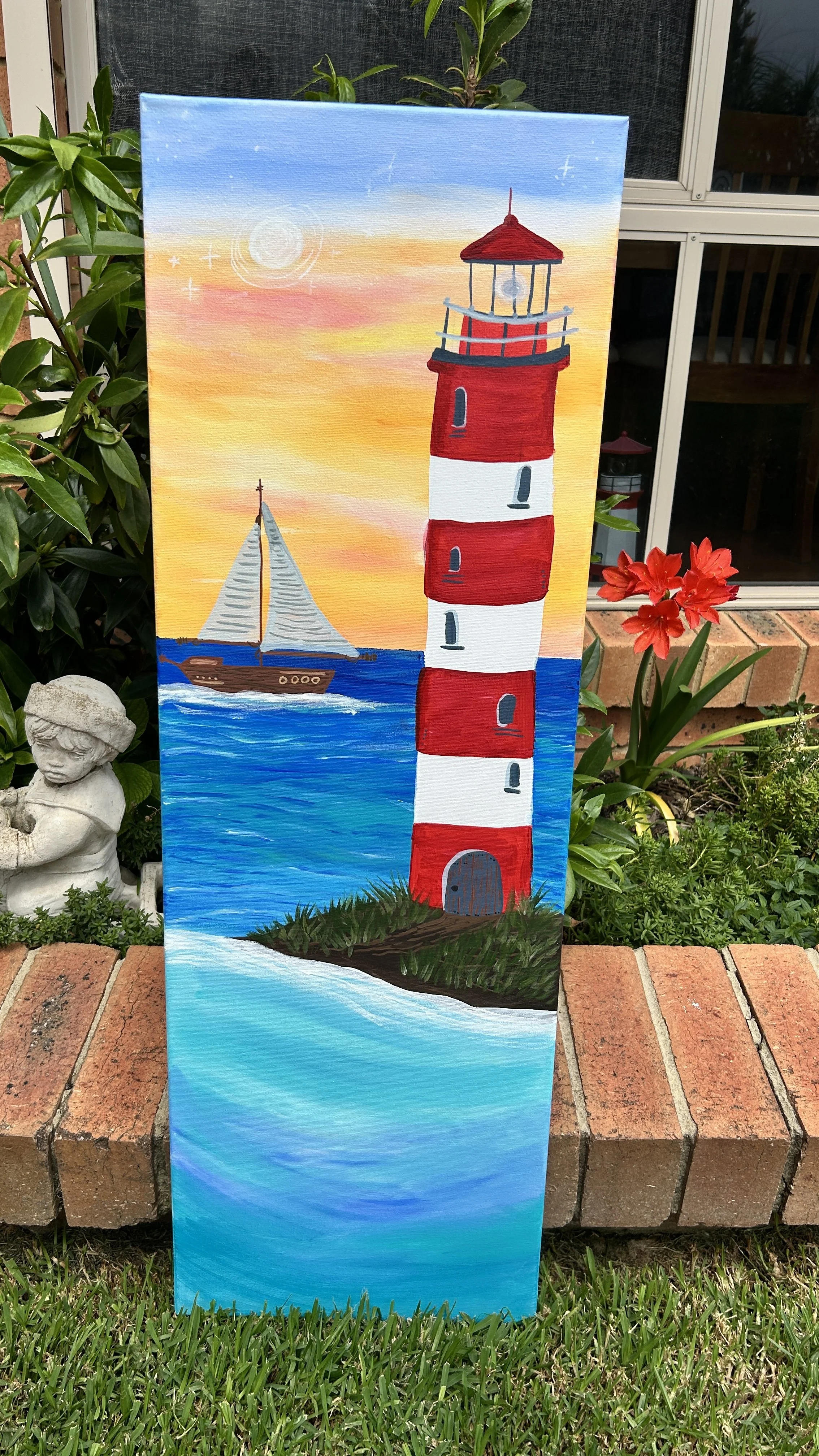 Painting of a red and white striped lighthouse near water, with a sailboat in the background during a sunset with a colorful sky.