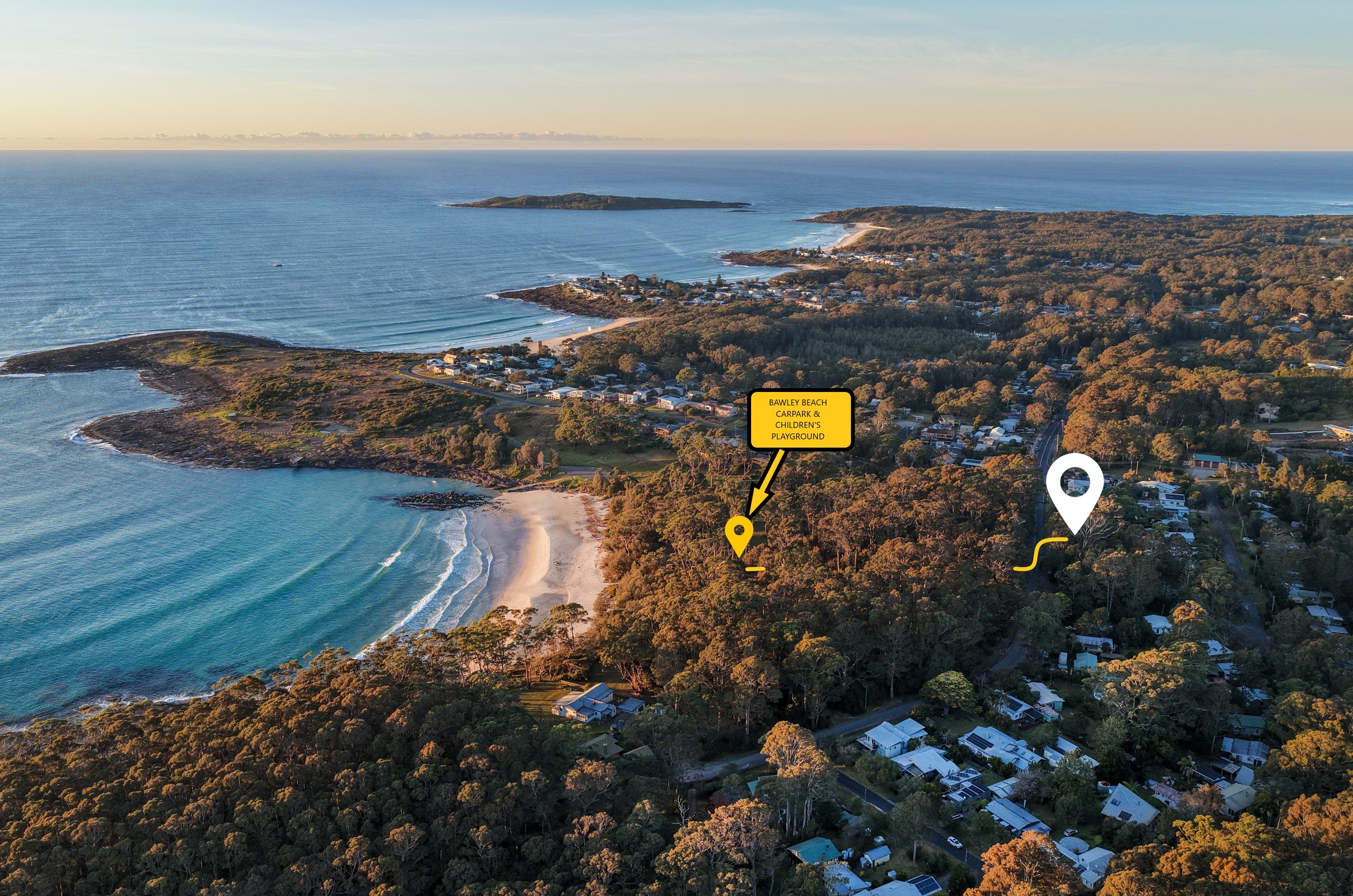 Aerial view of Bawley Beach with sandy shoreline, surrounding greenery, residential houses, and a calm ocean with small waves at sunset.