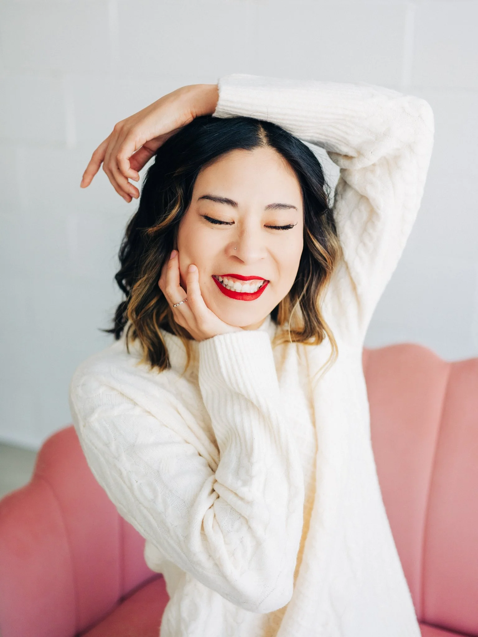 Woman smiling in a sweater with her hands raised above her head